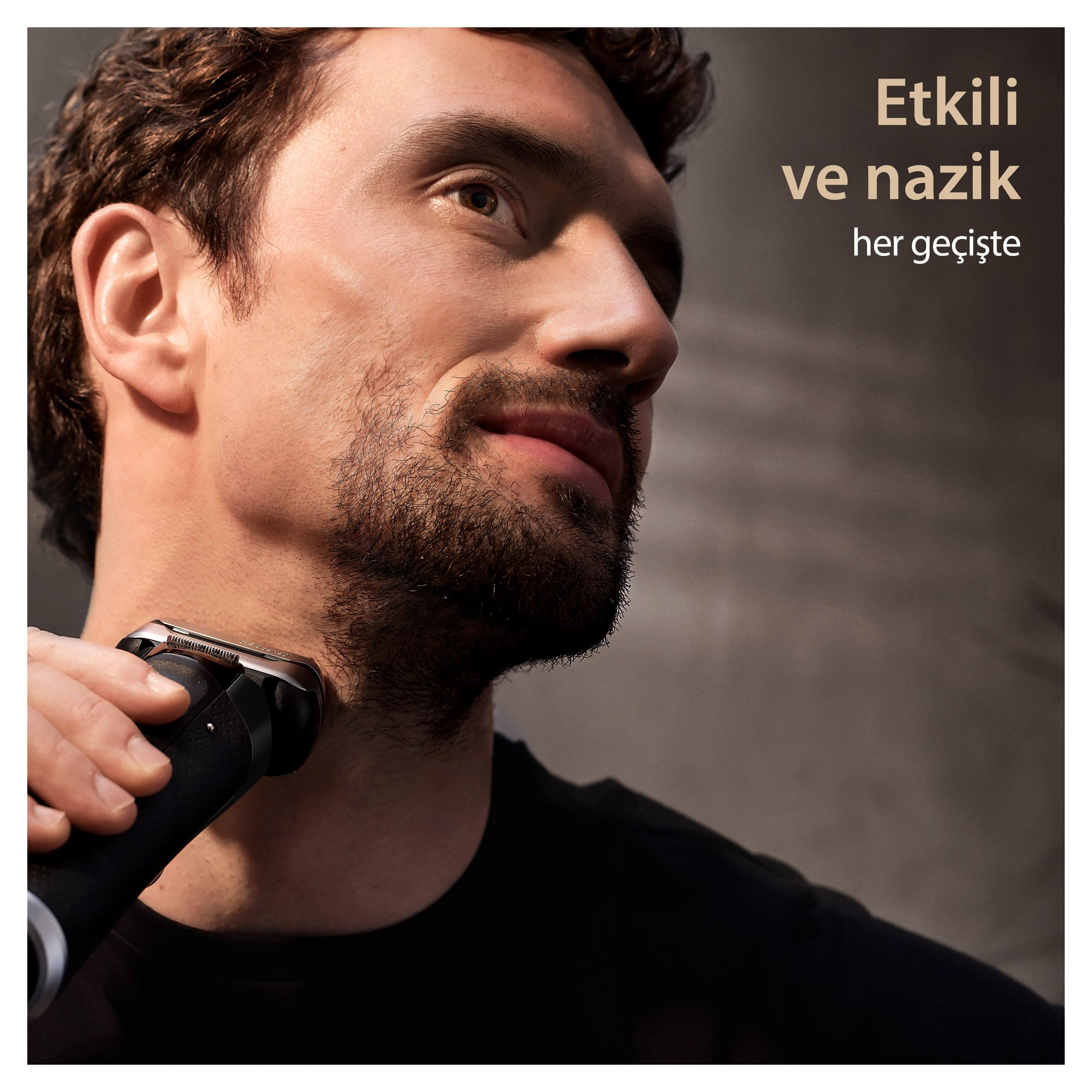 Adam, siyah bir elektrikli tıraş makinesi ile yüzünü tıraş ediyor, yakın çekim. Metin: Her geçişte etkili ve nazik.