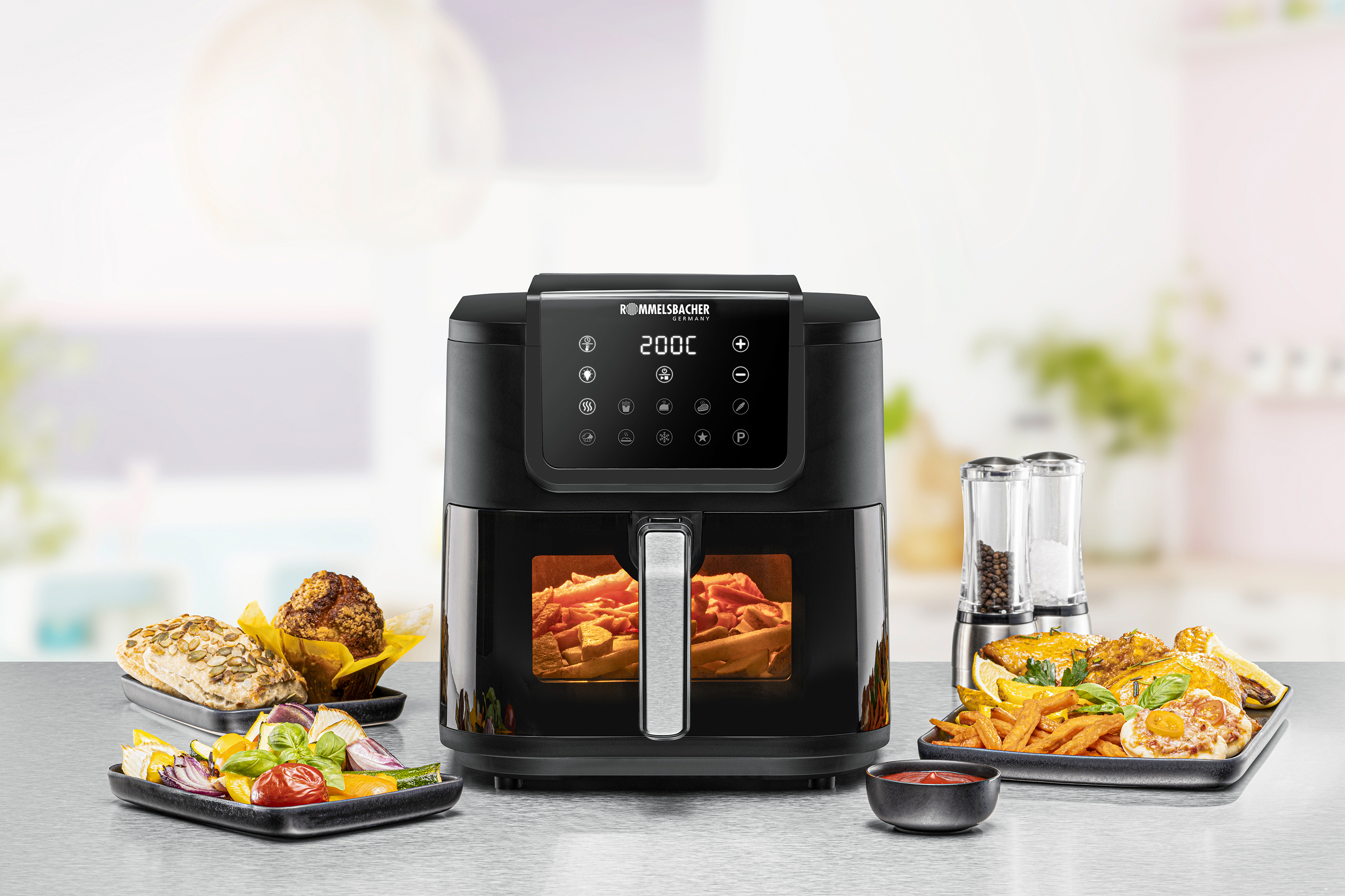 Eine schwarze Heißluftfritteuse mit Essen darin und auf Tellern, mit einer Kochtemperatur von 200°C.