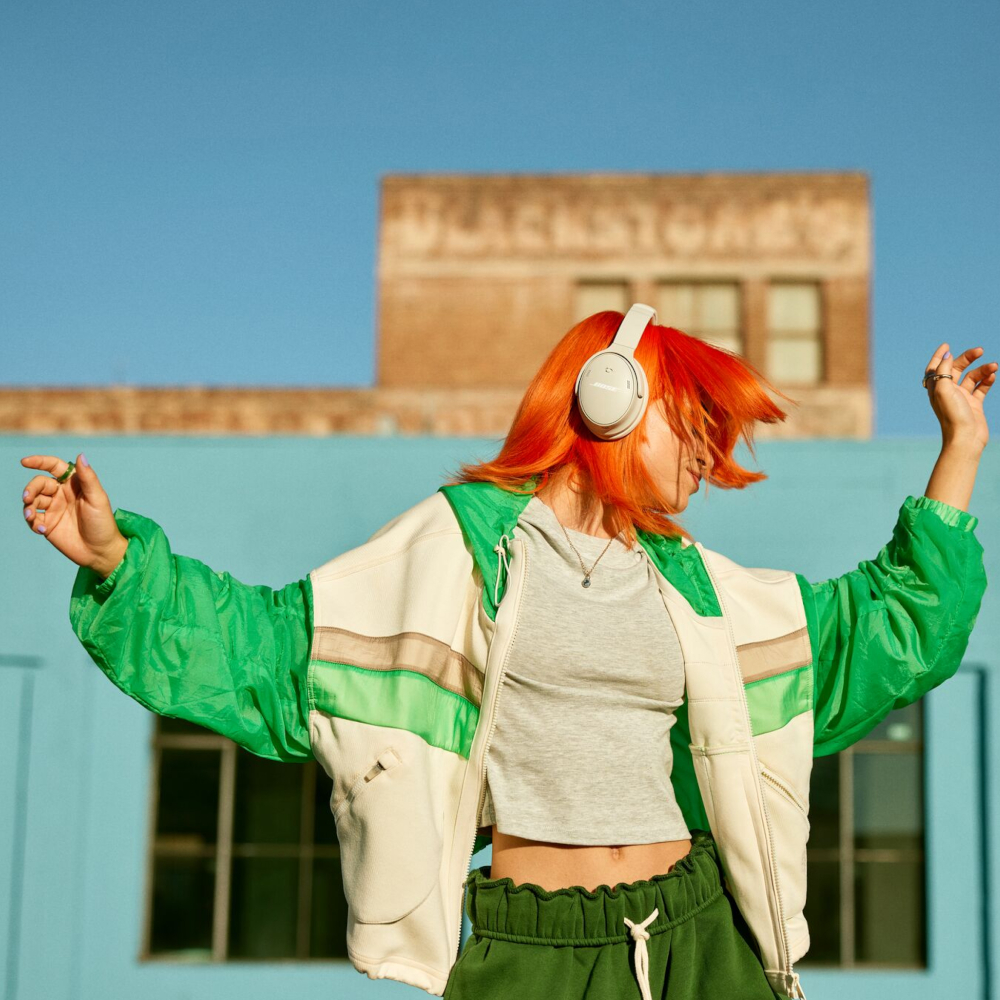 Woman dancing with orange hair and headphones.