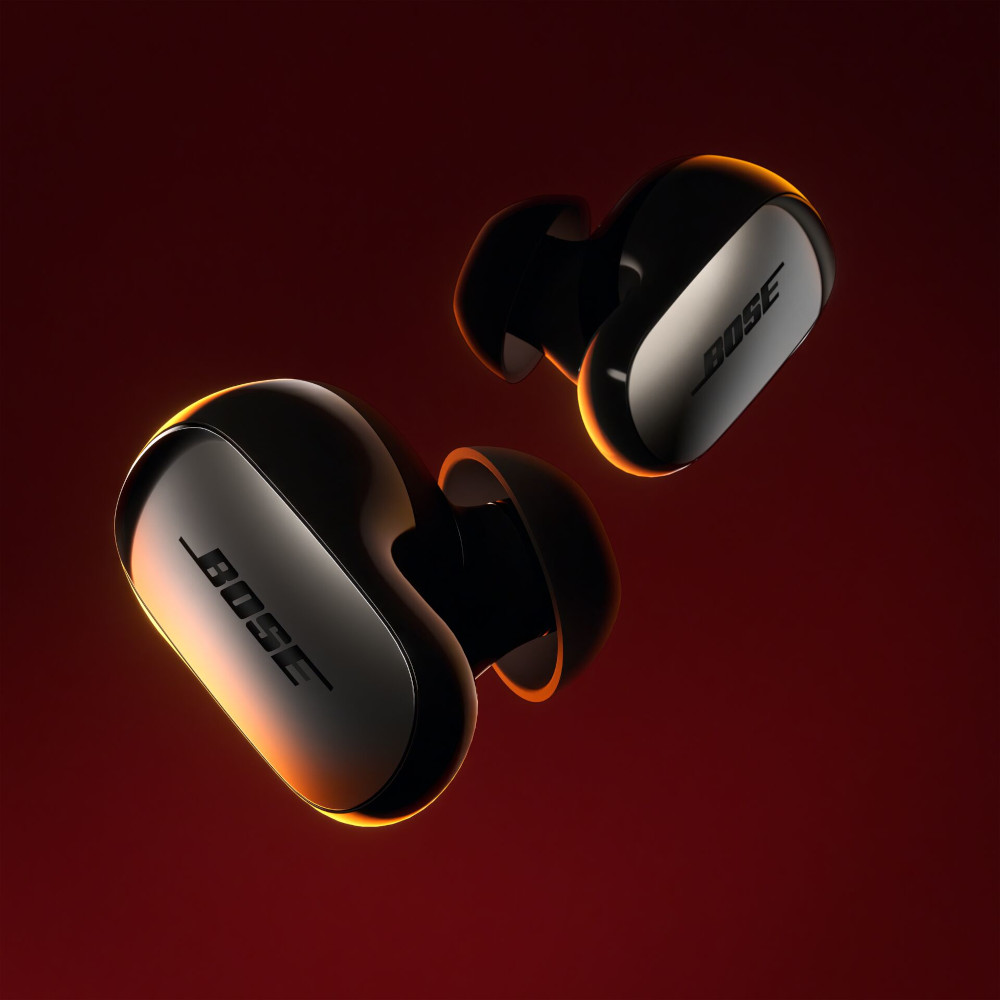 Two black wireless earbuds, with the BOSE logo, against a dark red background.