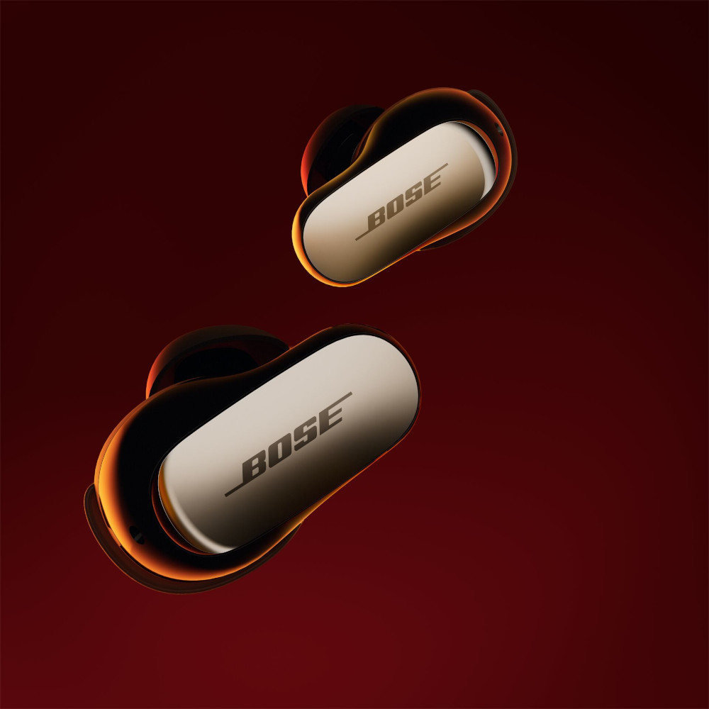 Two wireless earbuds, black with gold-colored accents, on a red background.