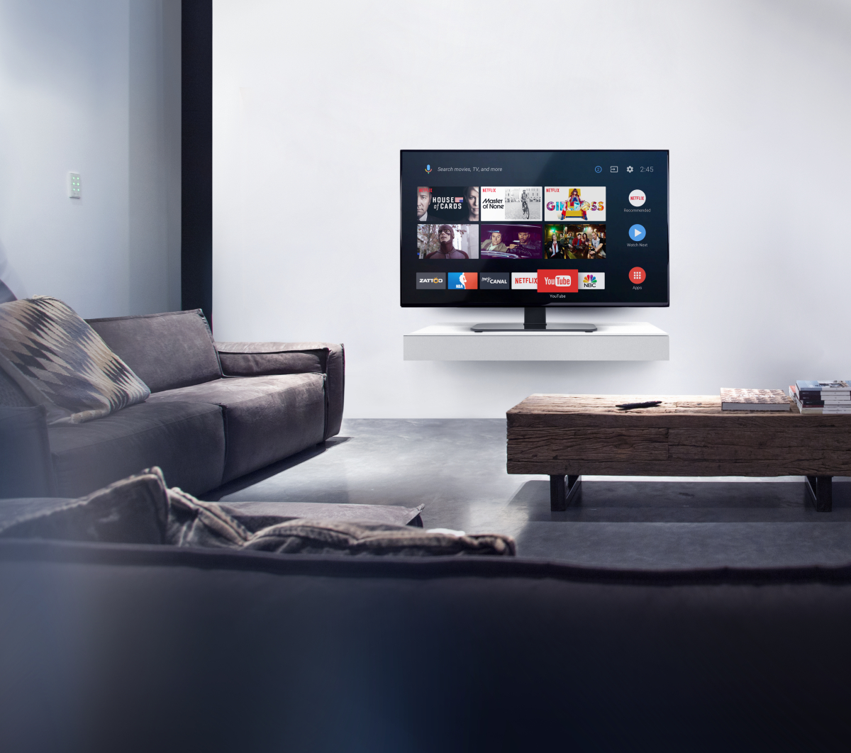 Ein Wohnzimmer mit Fernseher auf einem Regal und Sofa.