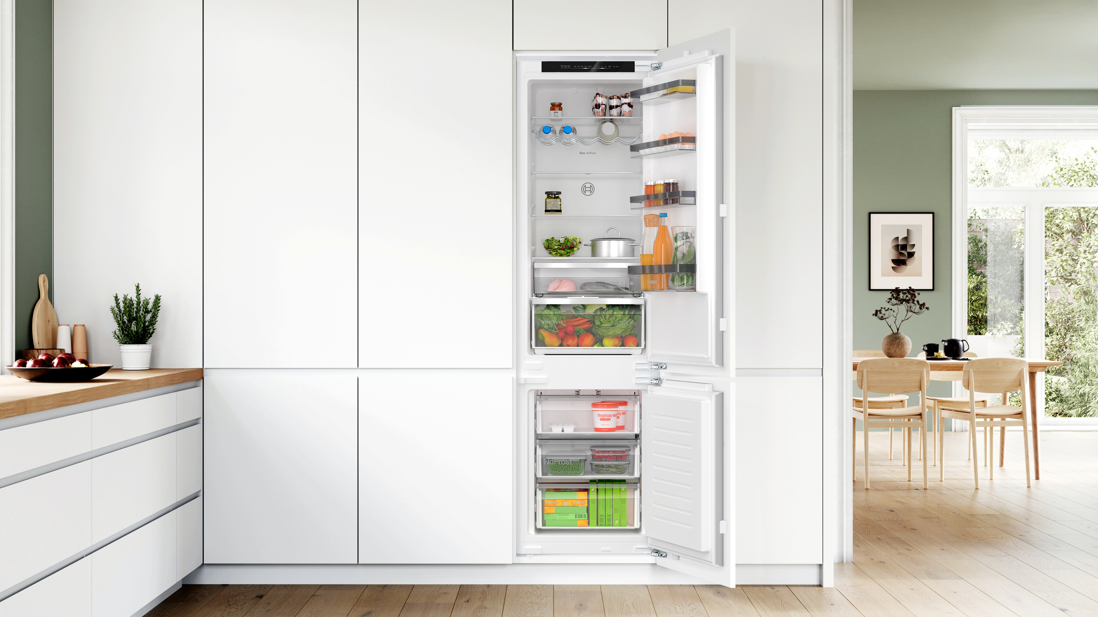 Weiße Küche mit Einbaukühlschrank. Kühlschranktür geöffnet, zeigt Lebensmittel in Fächern.