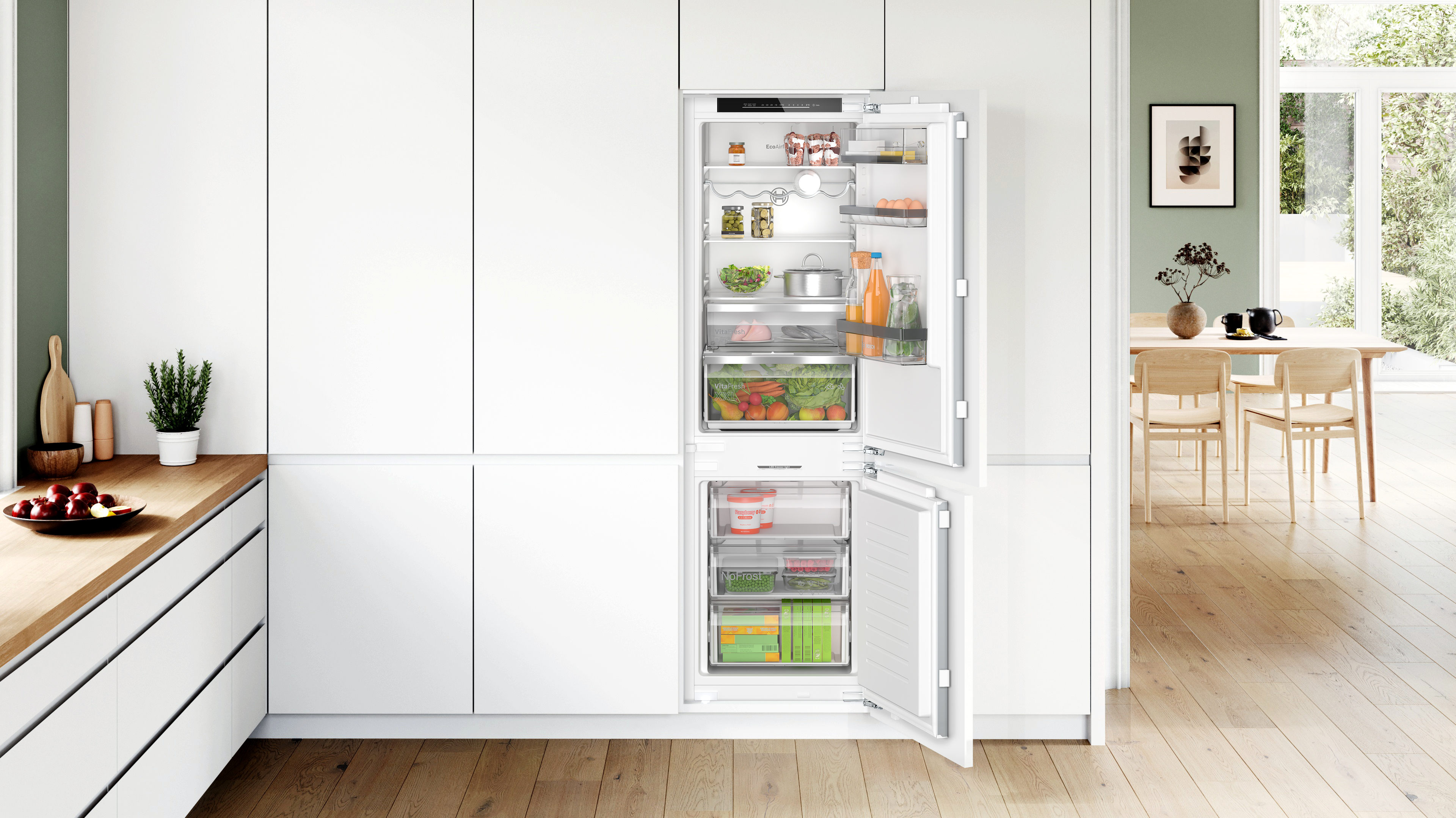 Eine moderne Küche mit Kühlschrank und Gefrierfach, beide Türen offen. Weiße Schränke und Licht.