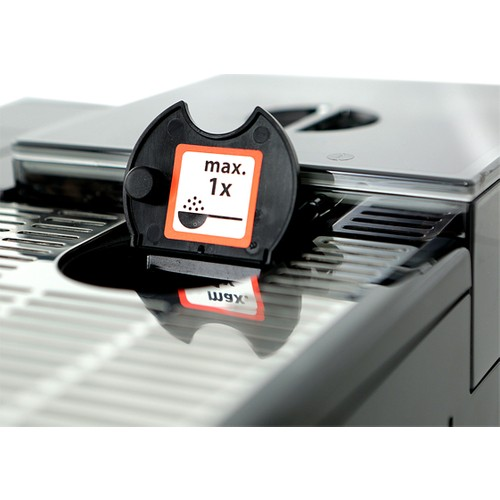 Maksimum 1x kaşık simgesi ve makinenin iç kısımları ile açık siyah bir kahve makinesi kapağı.