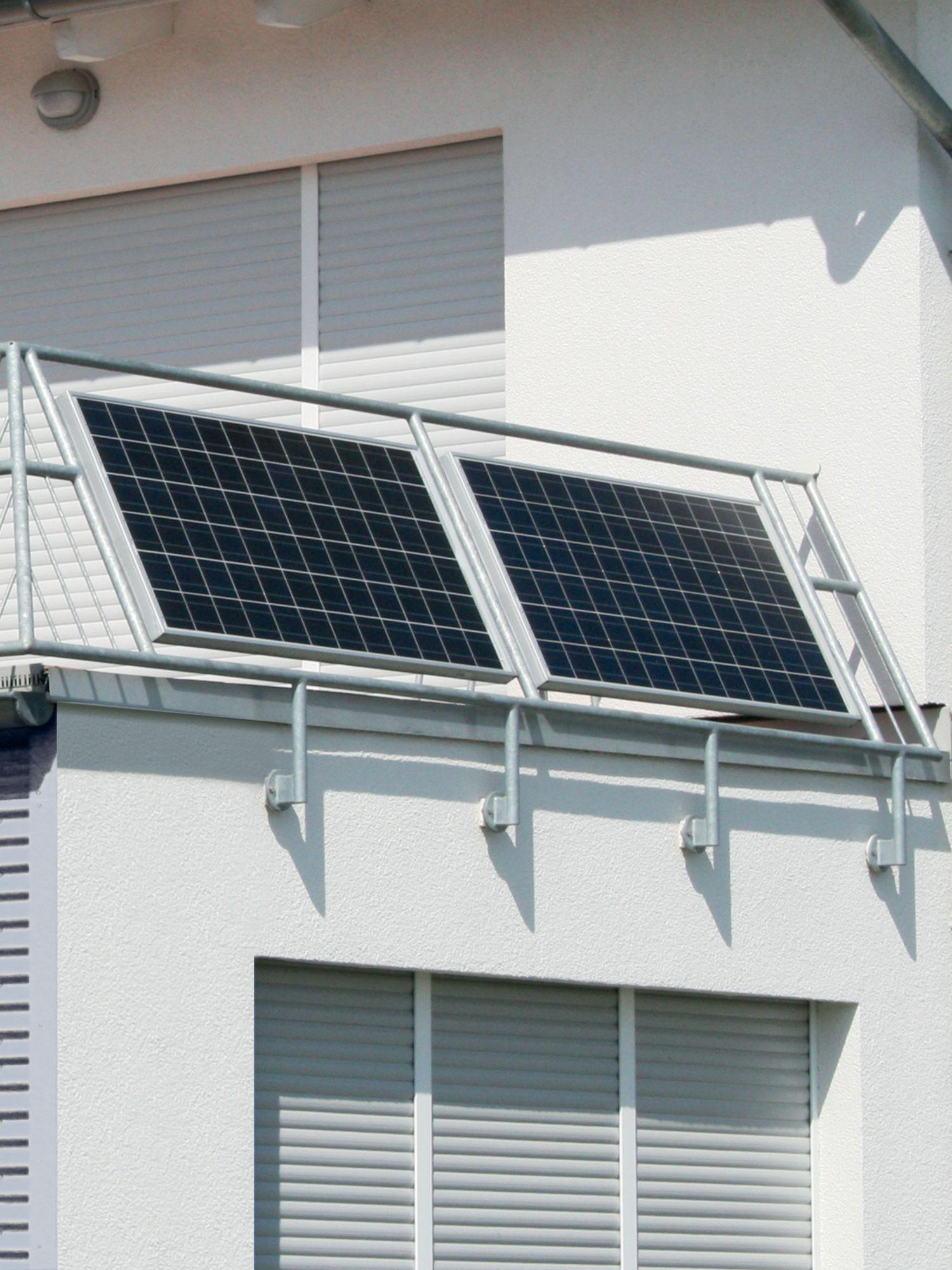 Solarpaneele auf einem Balkongeländer installiert. Weißes Gebäude mit Fenstern.