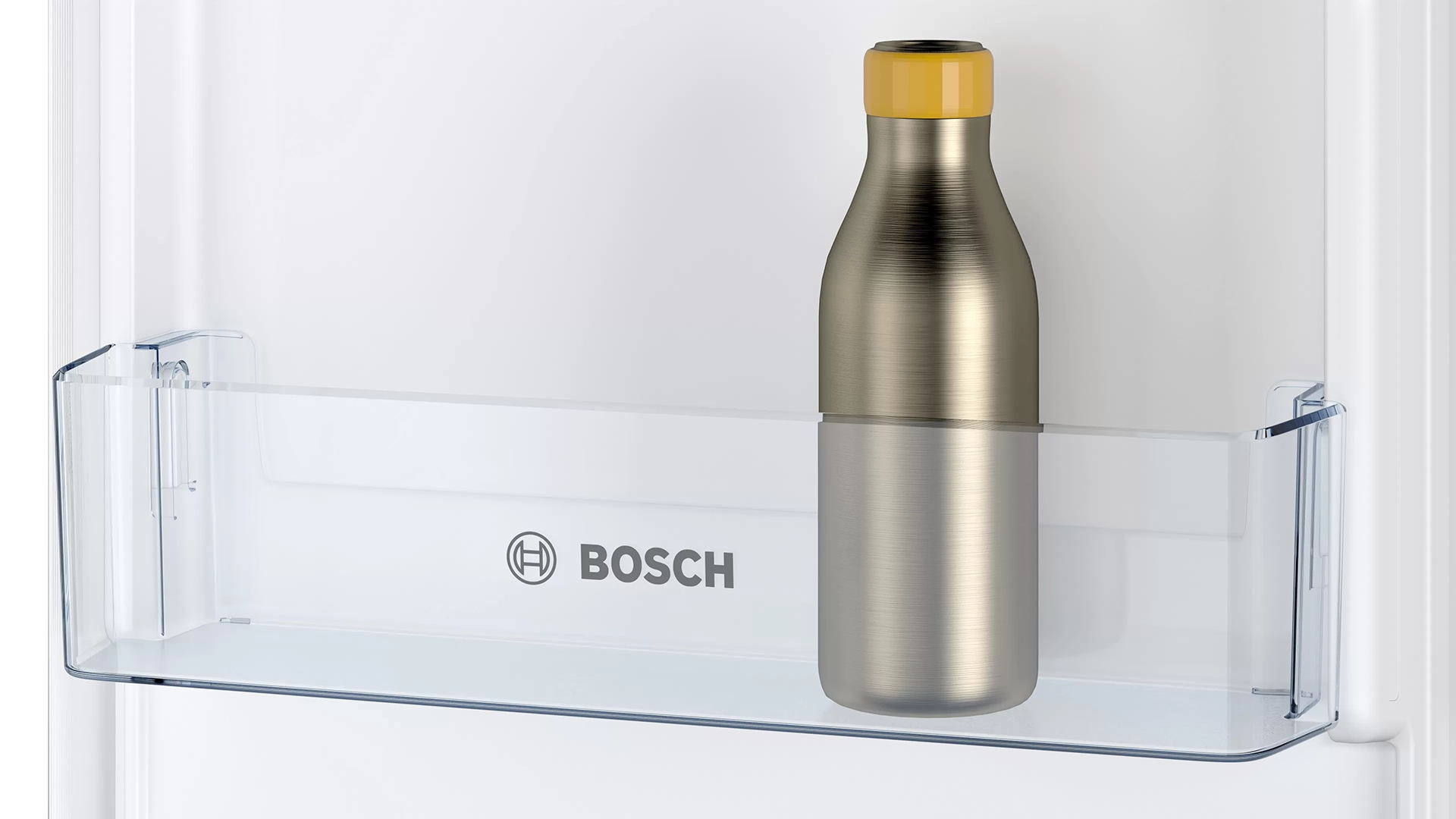 Hűtőszekrény polc egy ezüst színű kulaccsal, sárga kupakkal. Bosch logó látható.