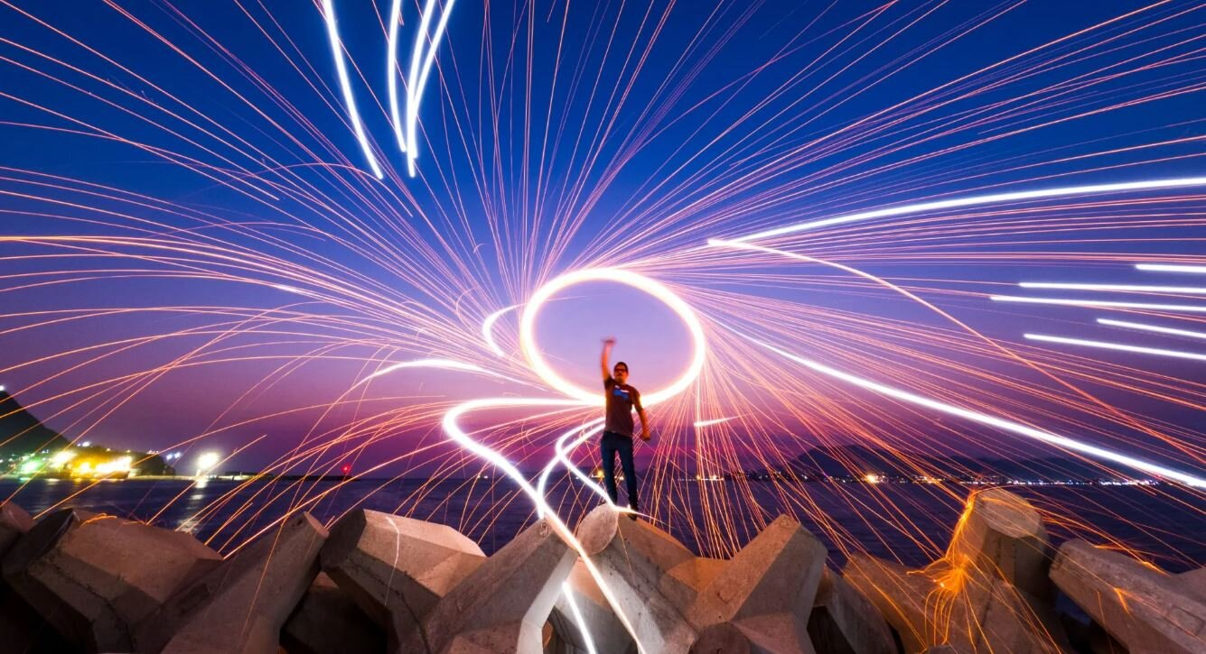 Osoba tworząca świetlne smugi za pomocą źródła światła w nocy.