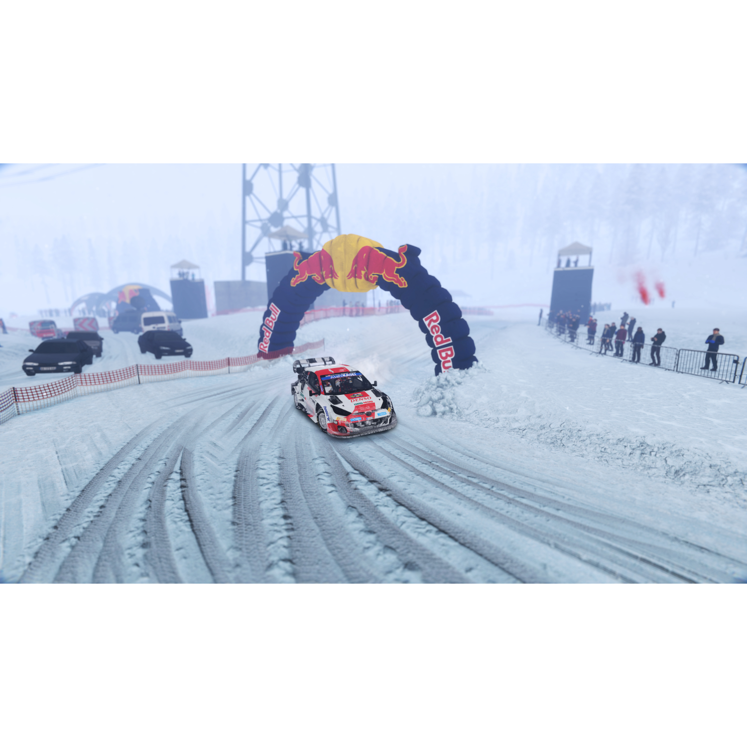 Een rallyauto op een besneeuwde baan, die onder een Red Bull-boog doorrijdt.