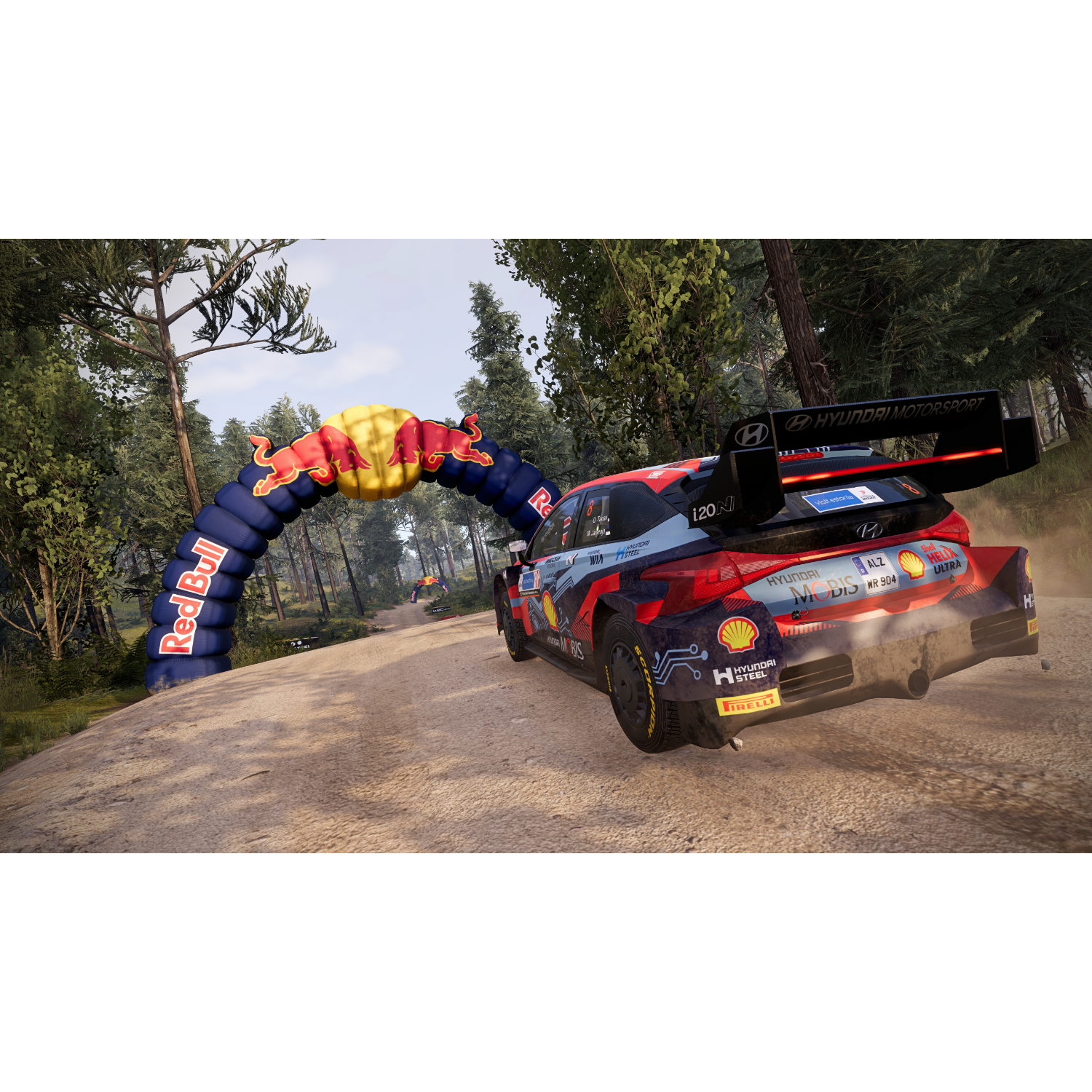 Een rallyauto die over een onverharde weg door een bos scheurt, langs een Red Bull-boog.