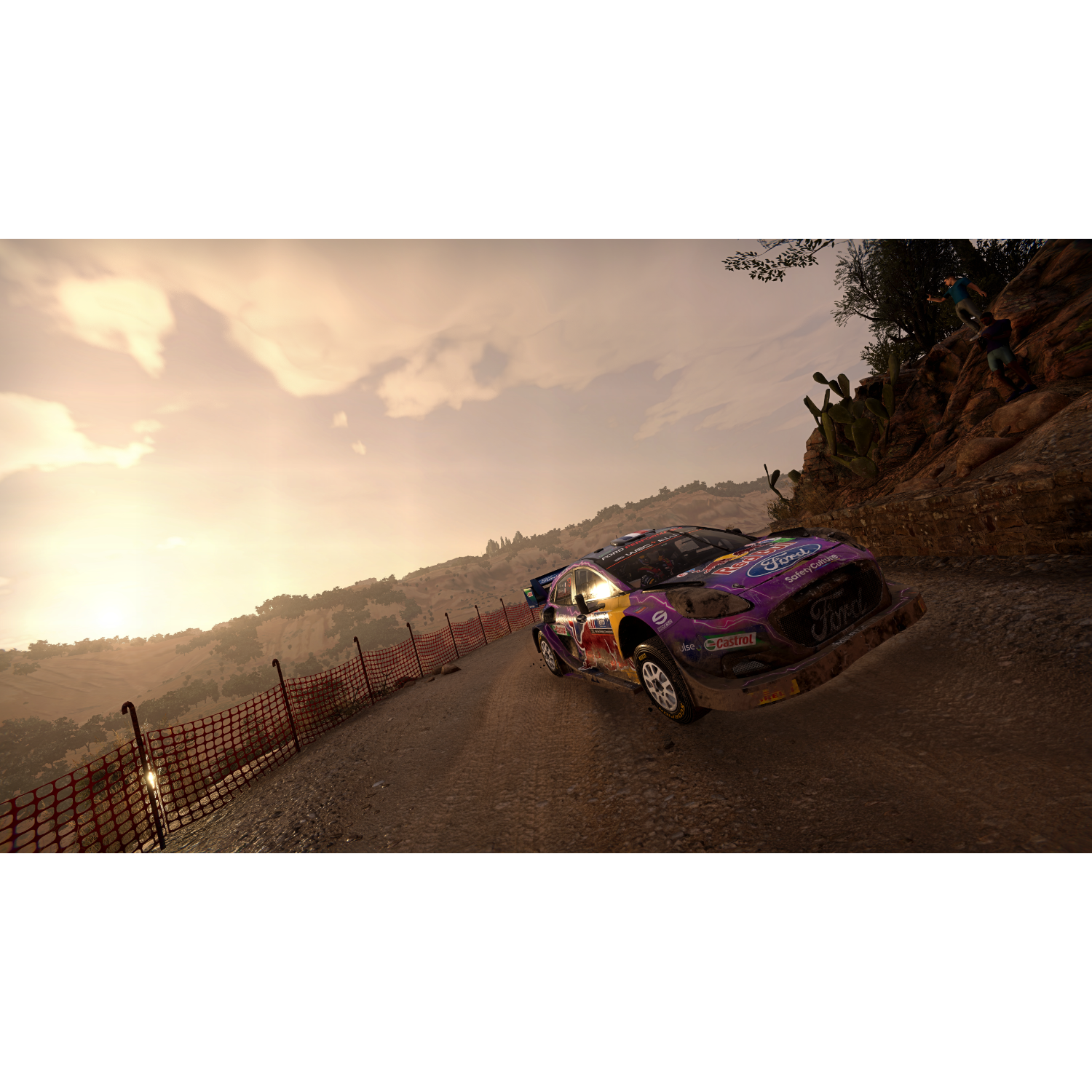 Een rallyauto op een onverharde weg in een berglandschap bij zonsondergang.