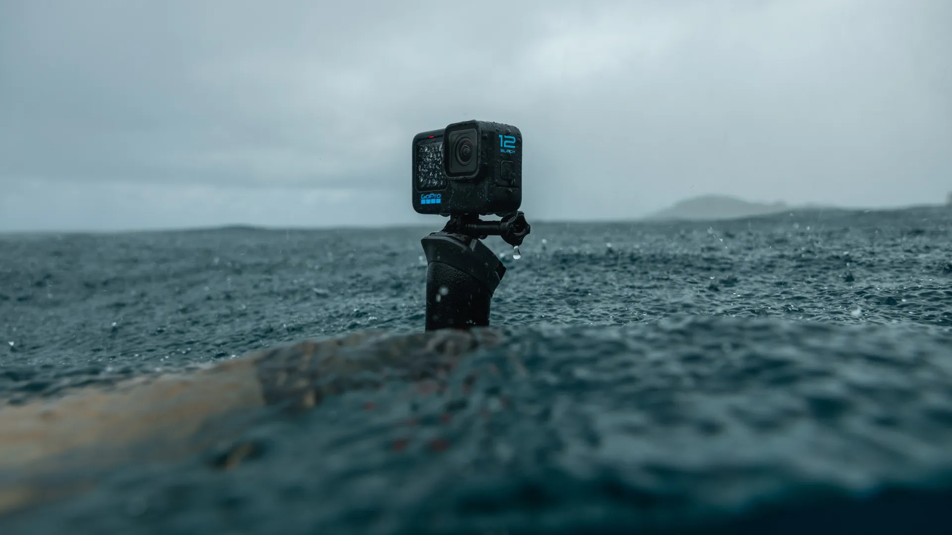 Siyah GoPro kamera bir çubuk üzerinde, yağmur ve dalgalı su ile okyanusta.