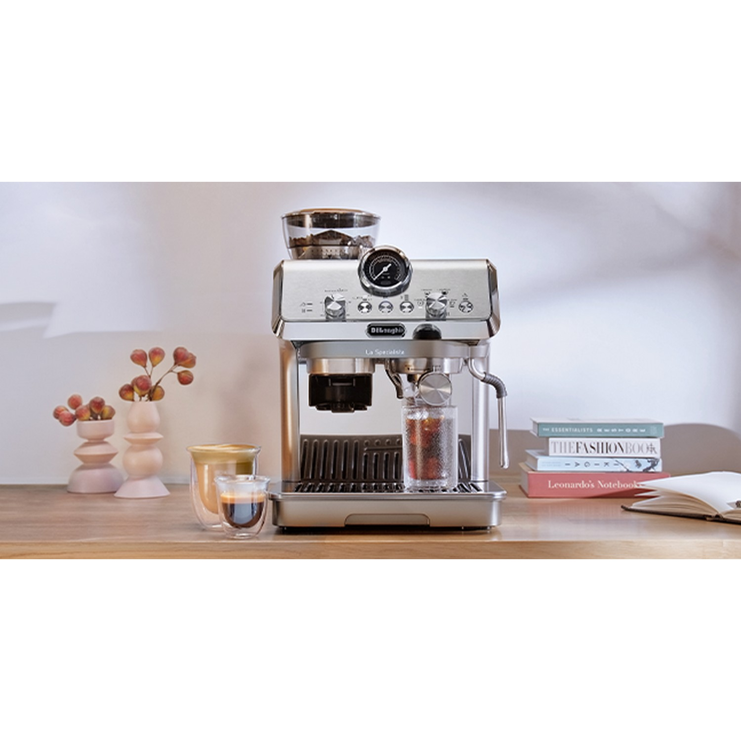 Espressomachine met molen, glazen karaf en koffiekopje op een houten oppervlak.