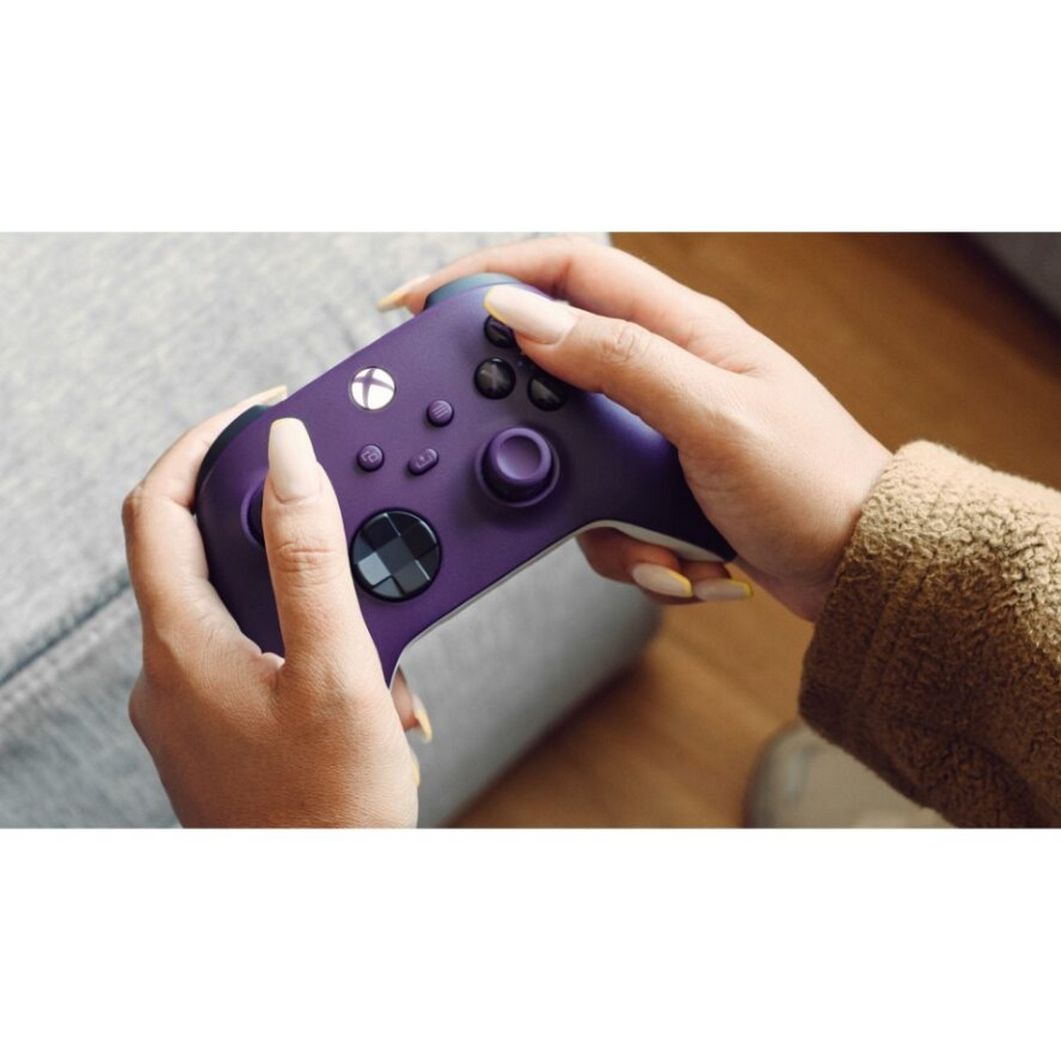 Mains tenant une manette Xbox violette avec des boutons, un plan rapproché.