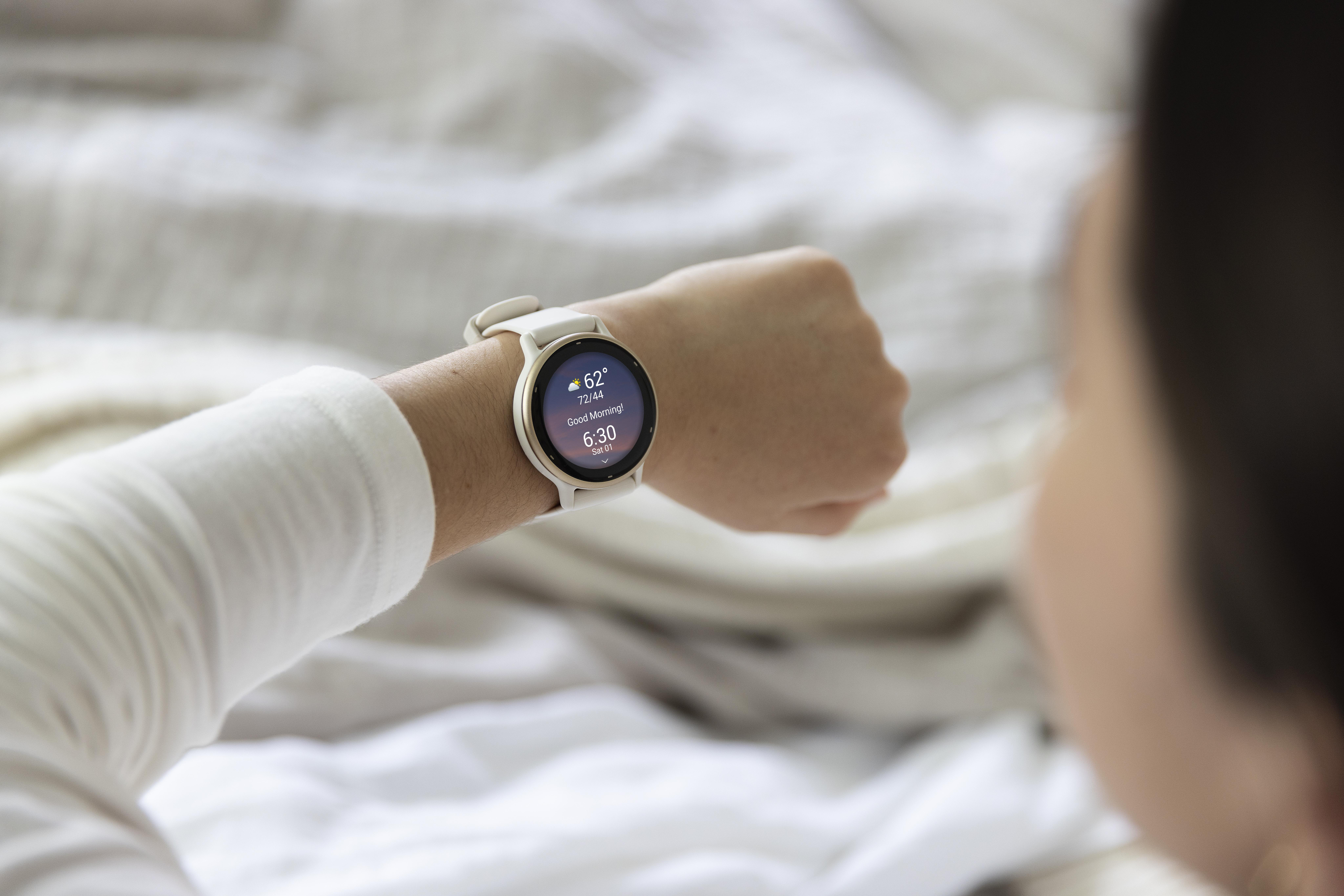 Eine Person, die eine Smartwatch trägt und auf den Bildschirm schaut. Die Uhr zeigt Zeit und Wetter.