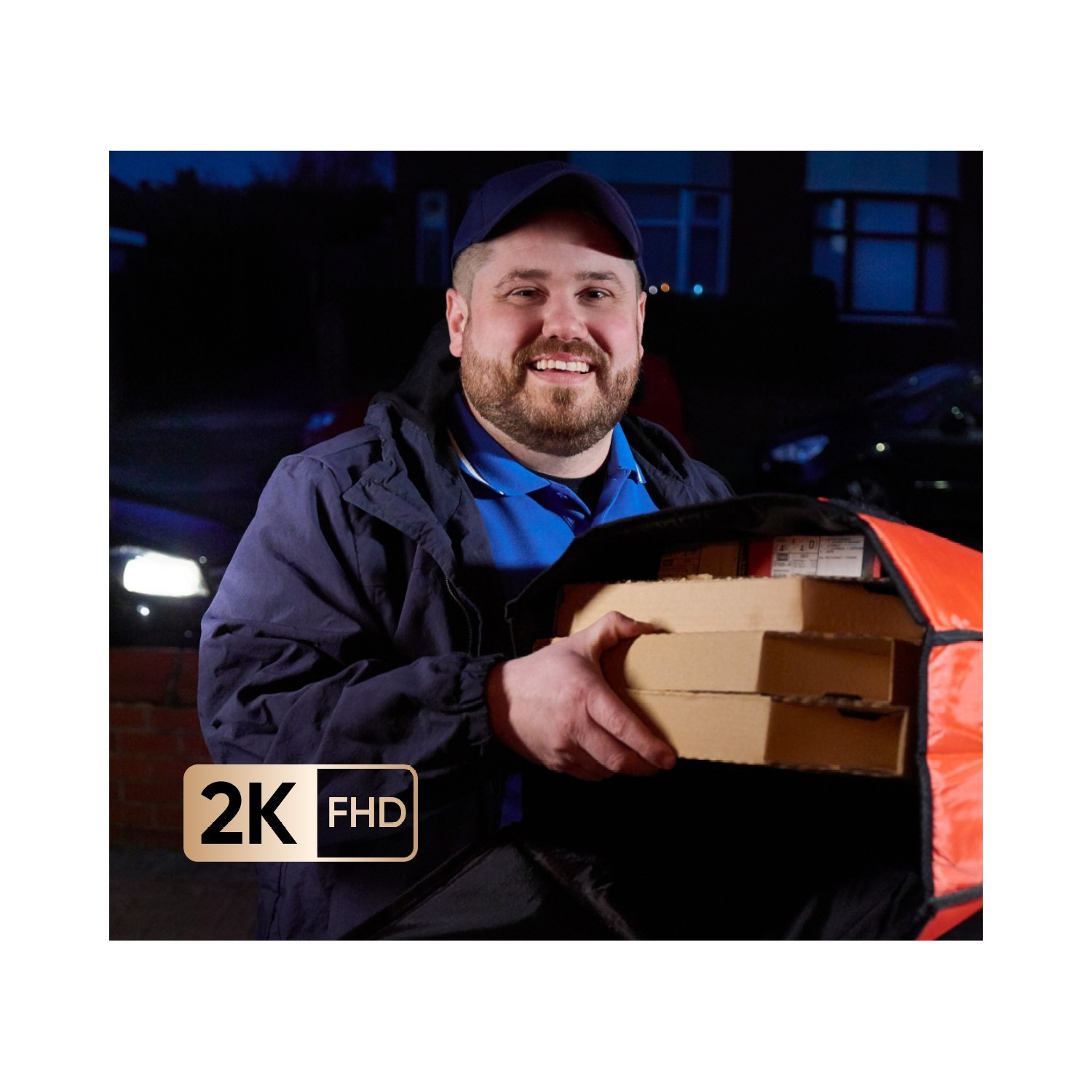 Een pizzabezorger lacht, met pizzadozen. Nachtscène, met auto's en huizen op de achtergrond.