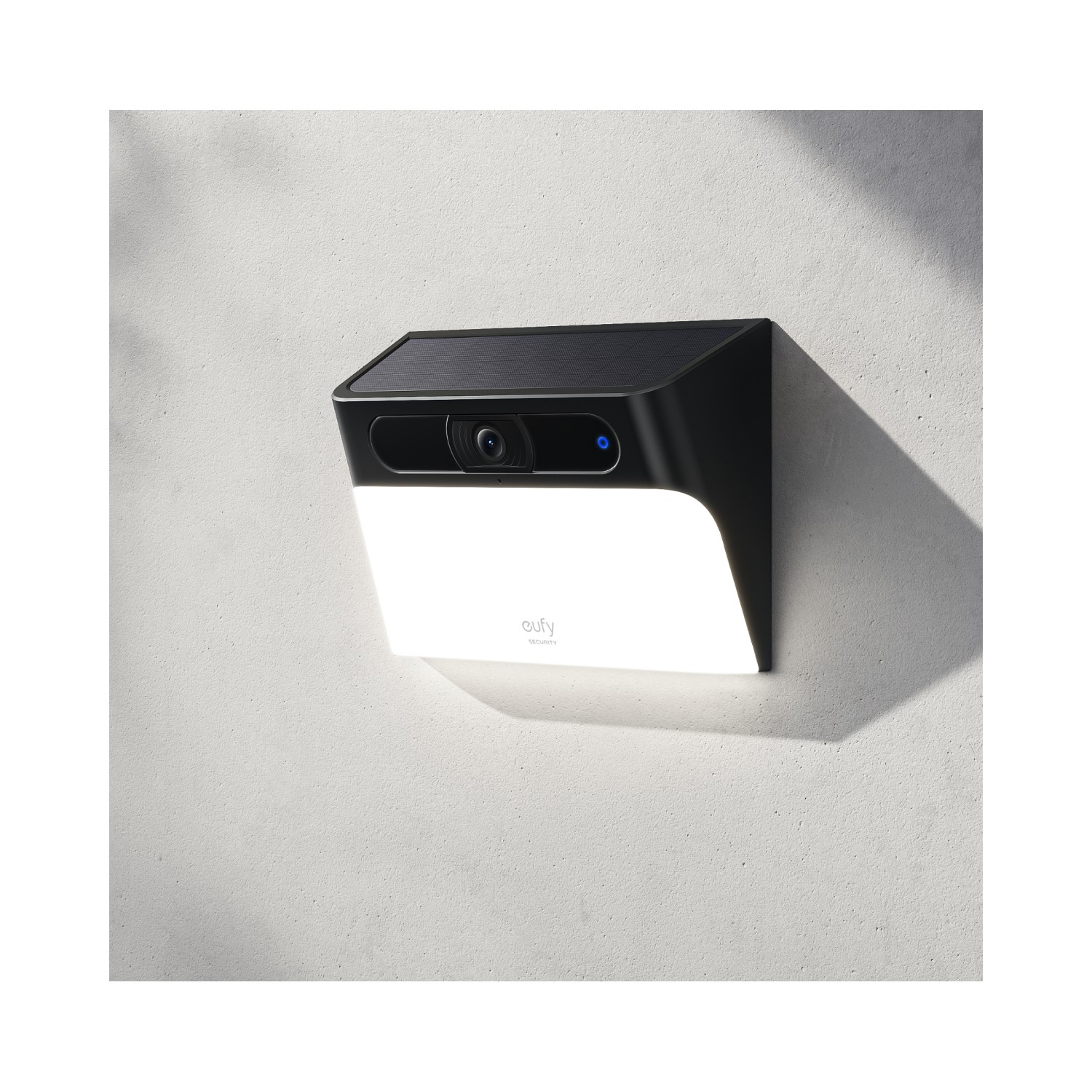 Eufy-beveiligingslamp met camera, gemonteerd op een witte muur, zwarte bovenkant.