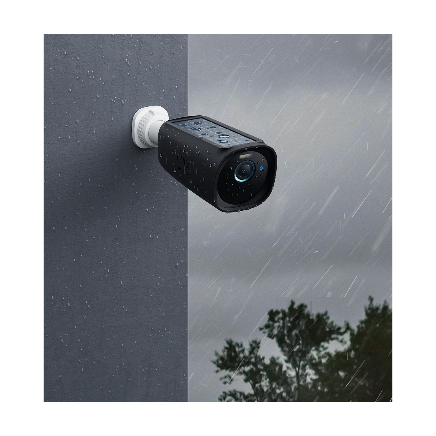 Une caméra de sécurité noire est montée sur un mur gris. Il pleut, et le fond est un ciel gris et des arbres.