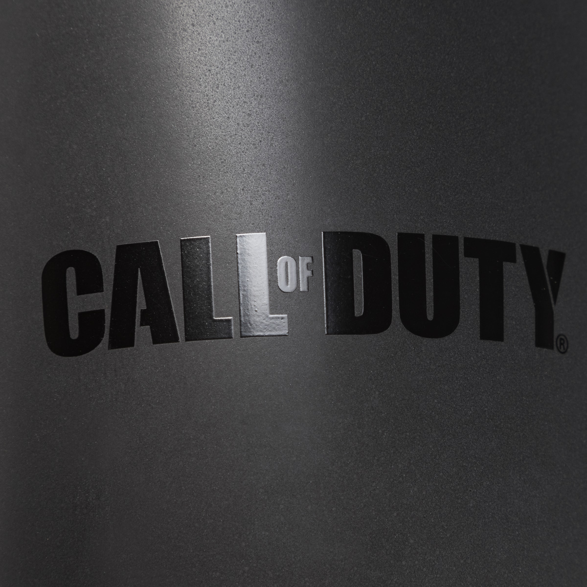 Die Wörter 'CALL OF DUTY' in schwarzer Schrift auf einer dunkelgrauen, strukturierten Oberfläche. Das 'L' ist reflektierend.