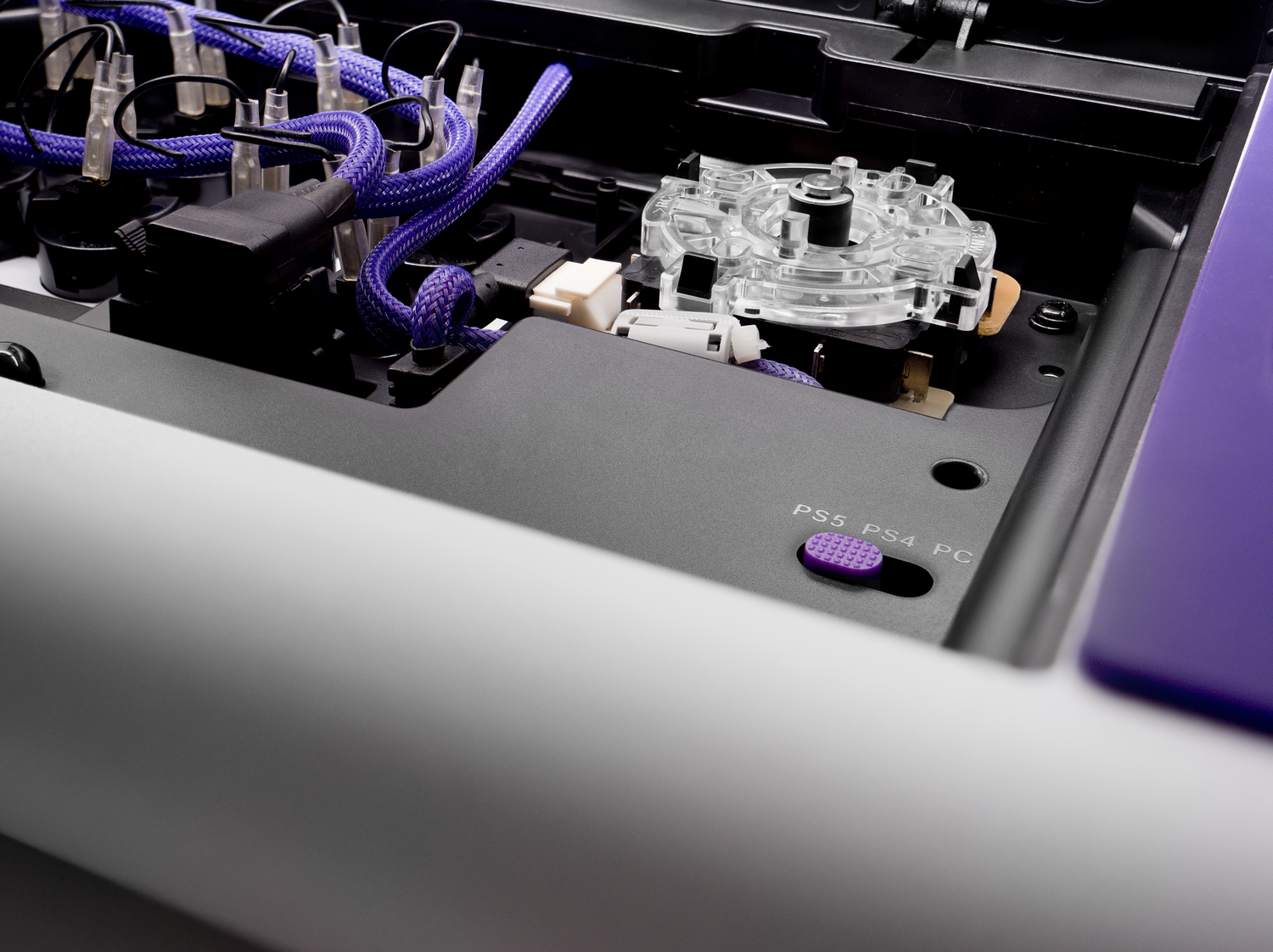 Primer plano de los componentes internos de una consola de juegos, incluyendo cableado y un panel de botones.