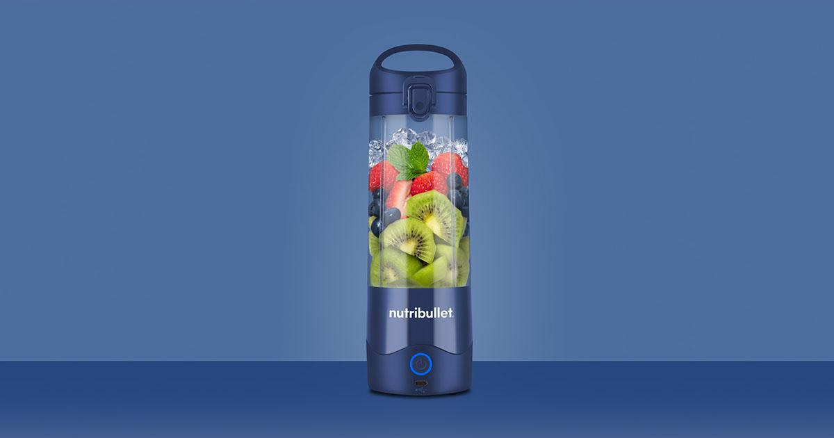 Transparente blaue Nutribullet-Mixerflasche gefüllt mit Früchten und Eis.