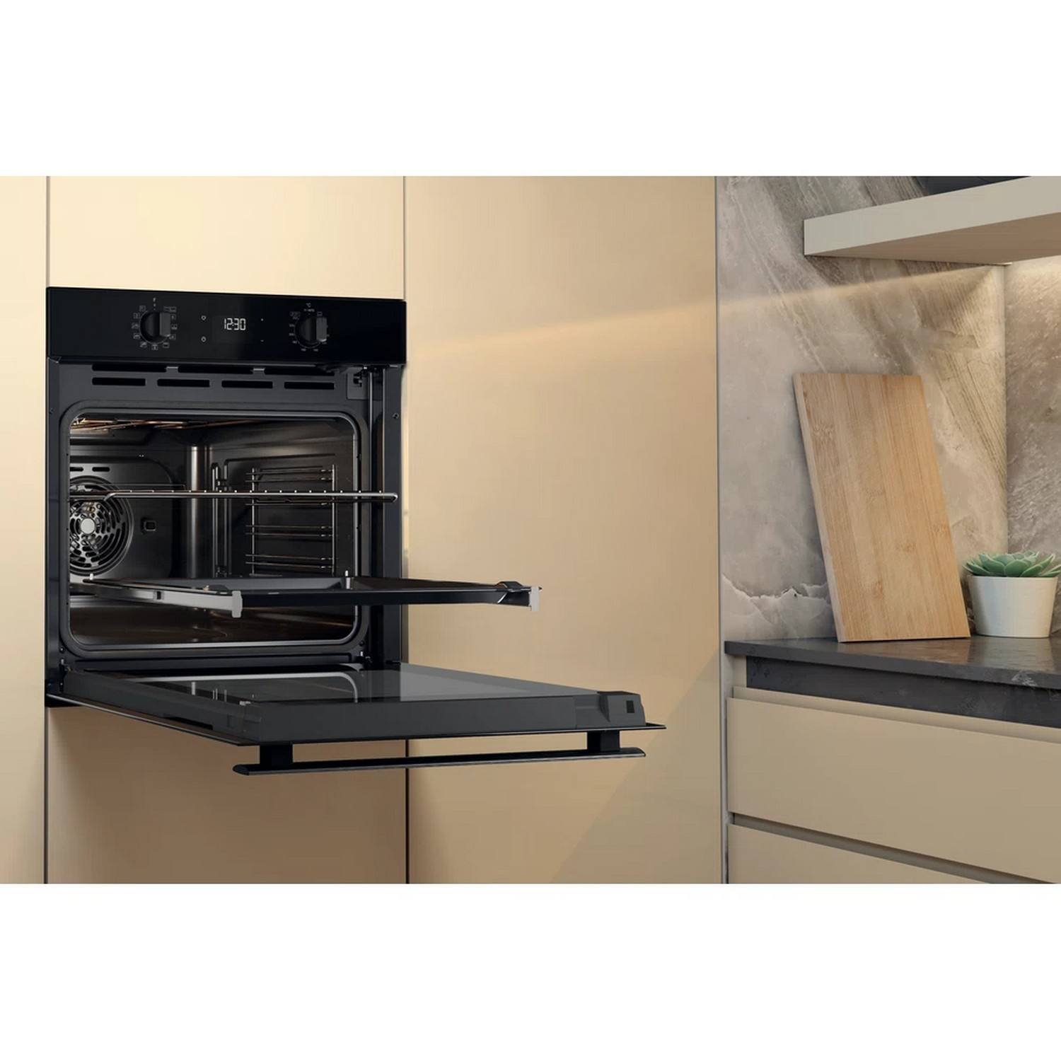 Oven with open door in a kitchen. Beige cabinets and wood cutting board.