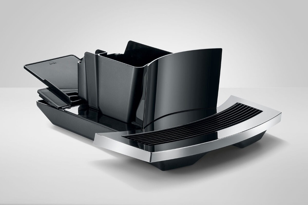 Zbiornik na wodę i tacka czarnego ekspresu do kawy, ze srebrnym akcentem na białym tle.