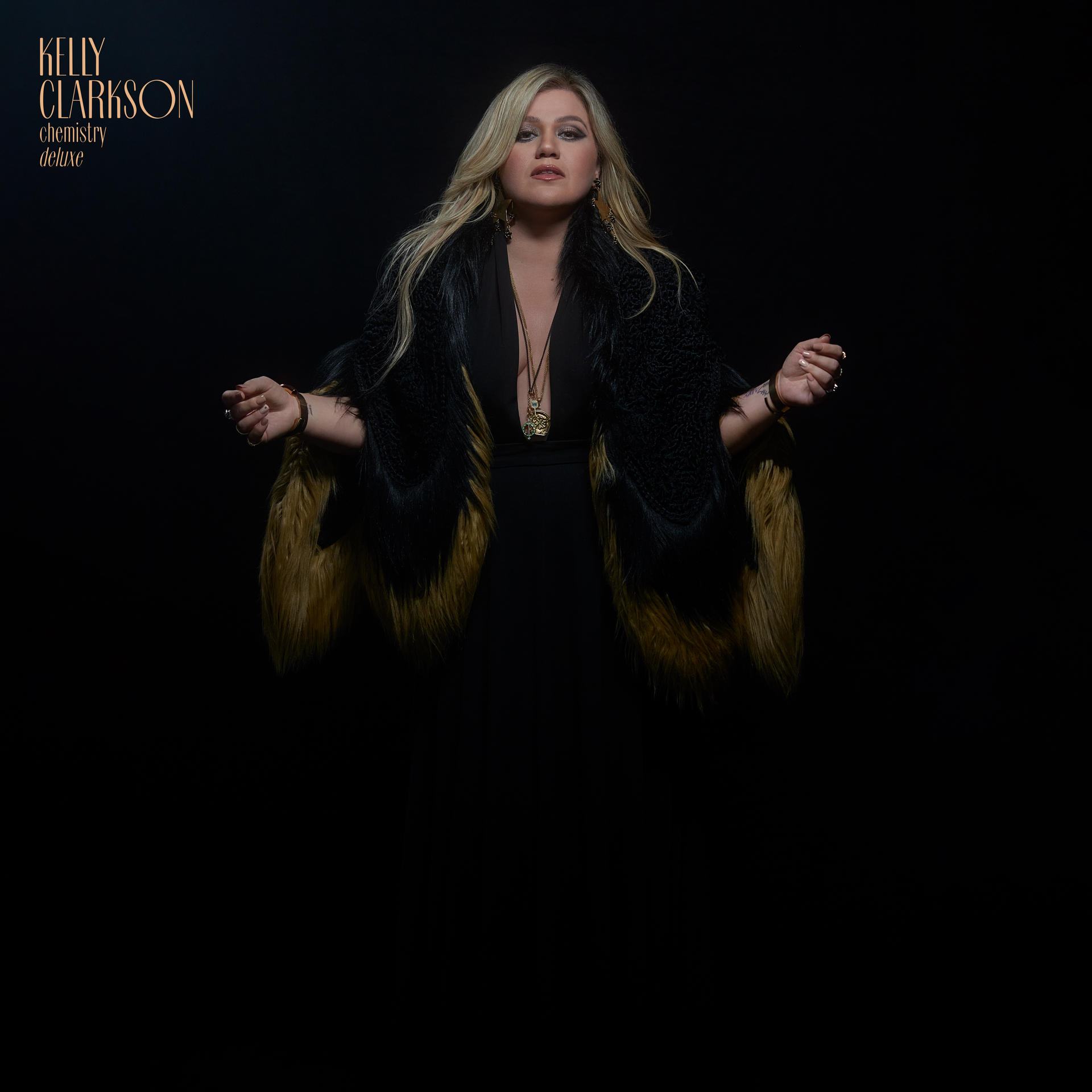 Kelly Clarkson album borítója. Fekete ruhát és bundát visel. Karjai ki vannak nyújtva.