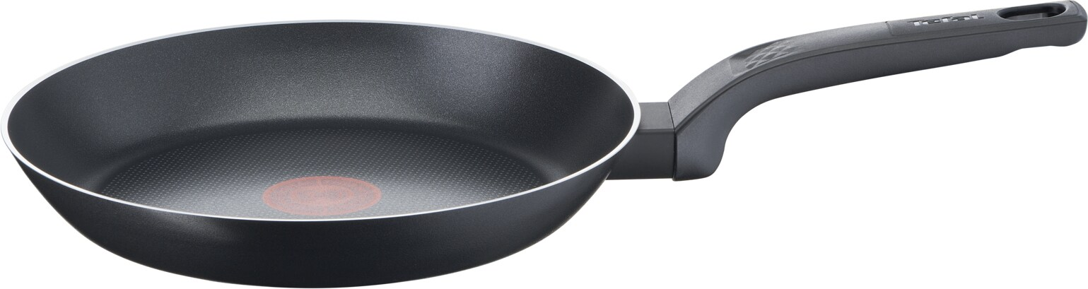 Poêle noire avec un point rouge au centre. La poêle a une poignée et un bord argenté.