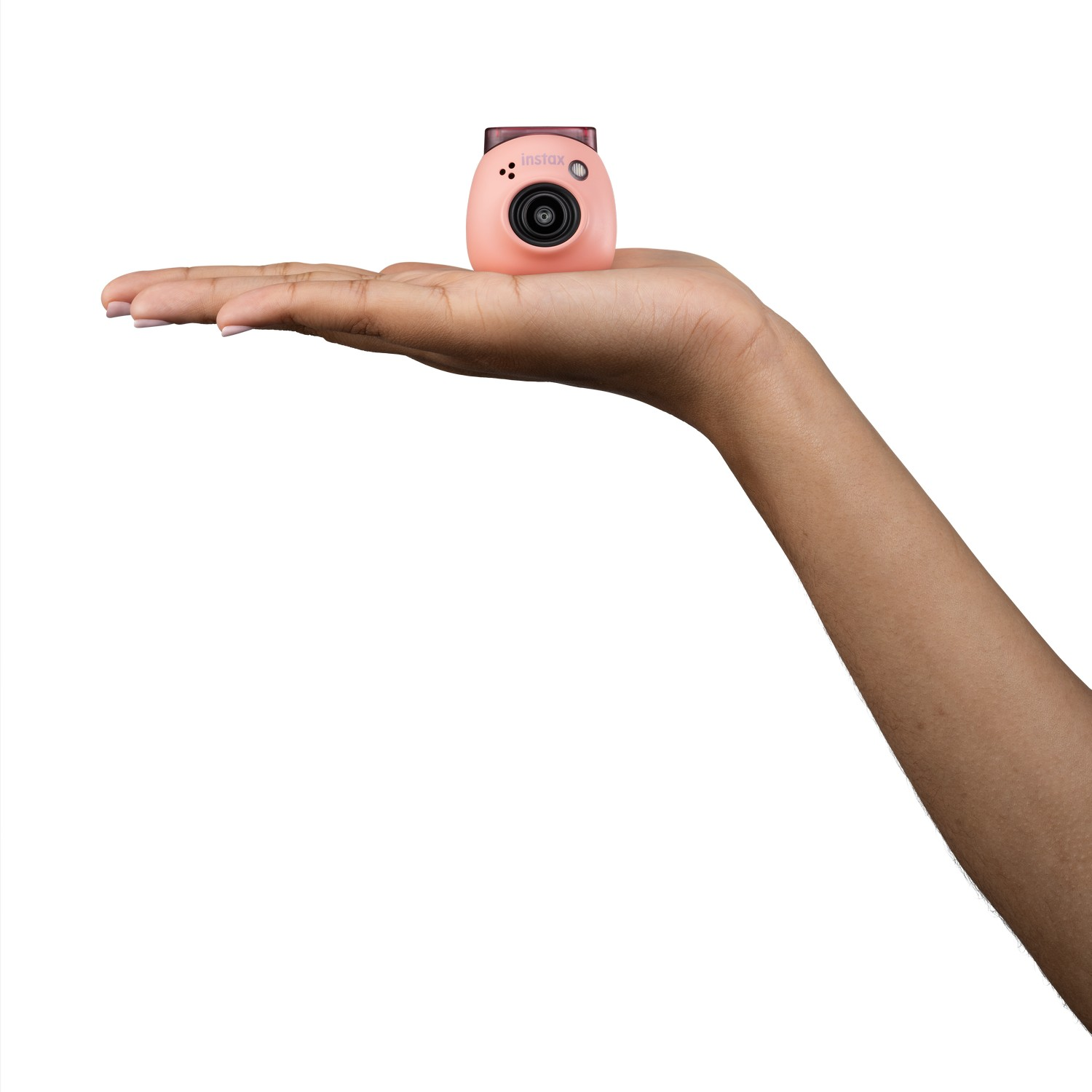 Hand die roze Instax camera vasthoudt. Witte achtergrond. Camera heeft een lens.