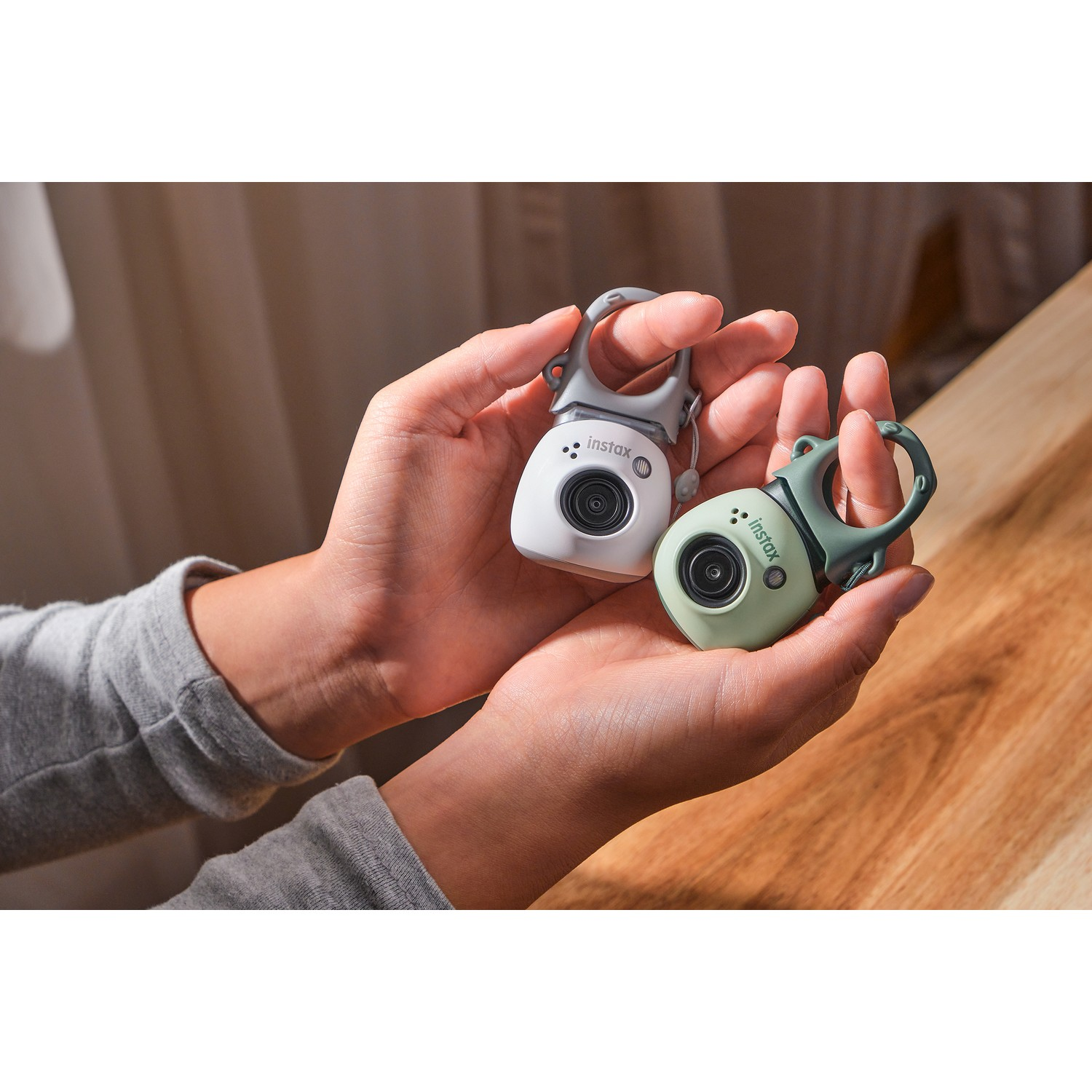 Twee kleine, witte en groene camera's in handen; gebruikt voor het vastleggen van beelden.
