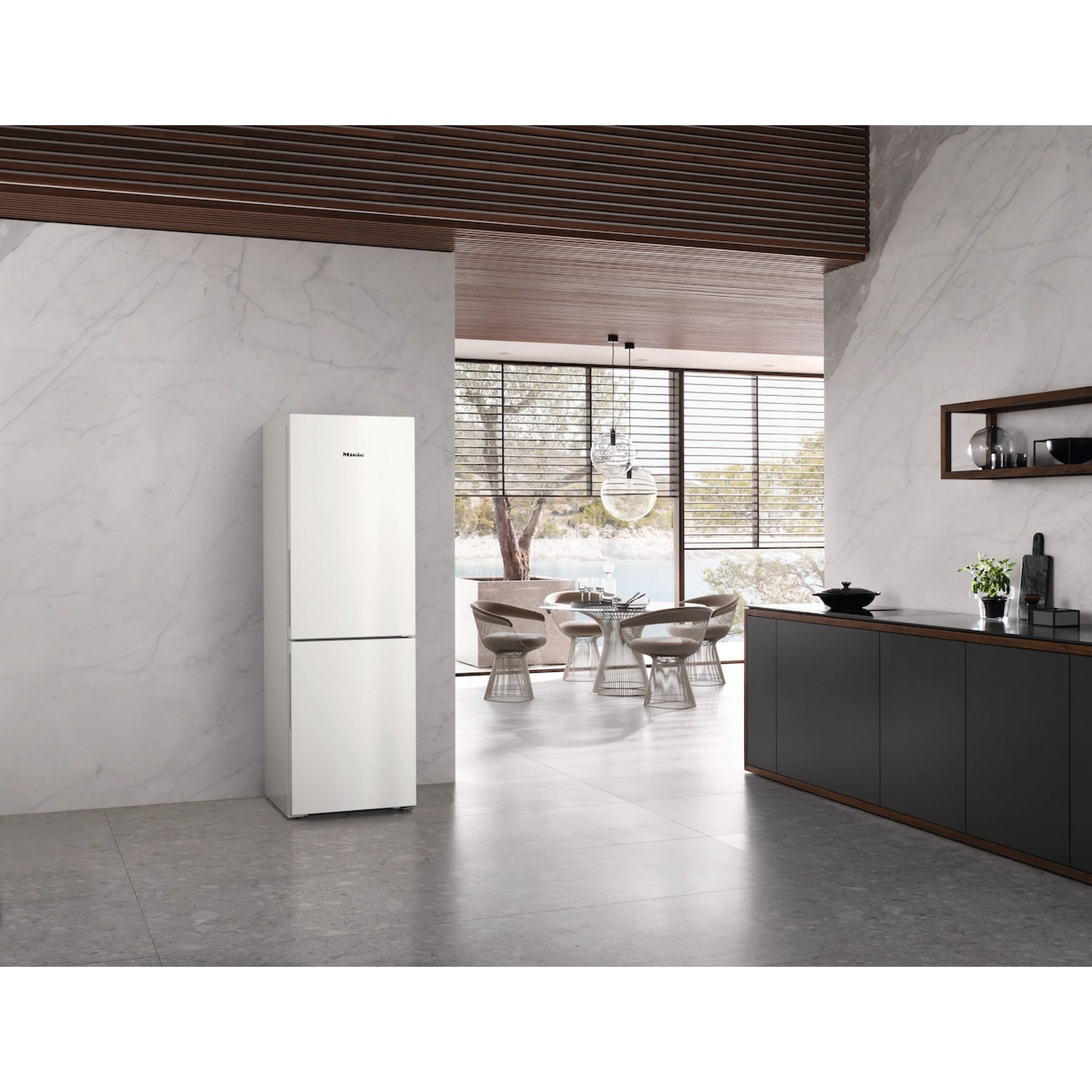 Réfrigérateur blanc avec dessus gris, dans une cuisine moderne avec murs en marbre et boiseries.