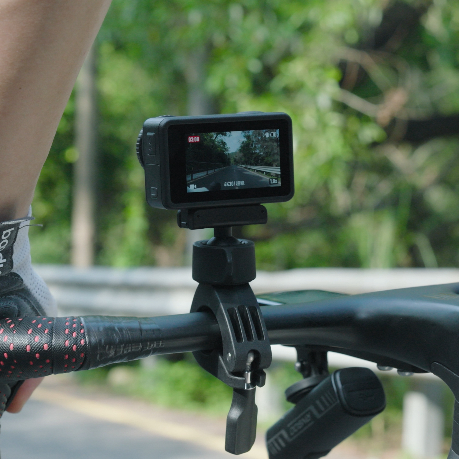Persona che va in bicicletta con una fotocamera montata sul manubrio. La fotocamera è nera.