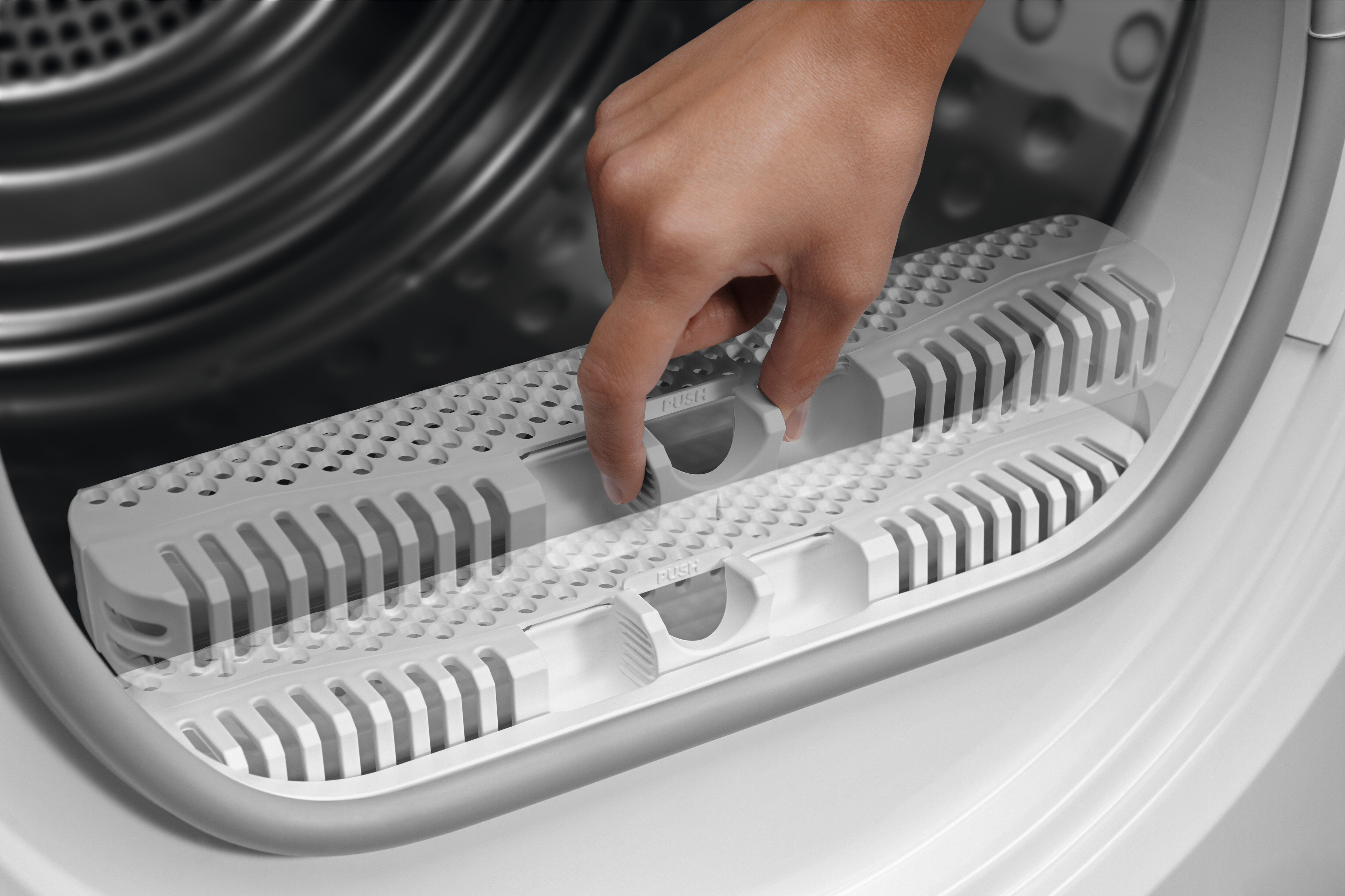 Une main retire un filtre blanc d'un sèche-linge blanc.