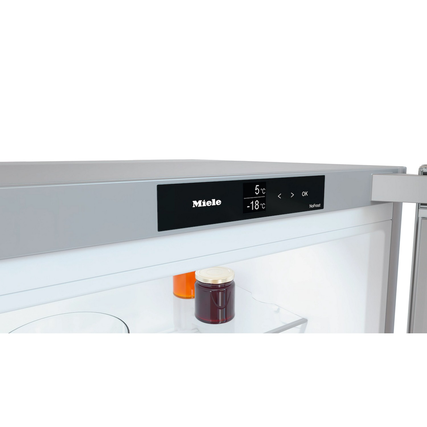 In een koelkast. Een Miele-display toont temperaturen. Potten met jam staan op een plank. De koelkast is open.
