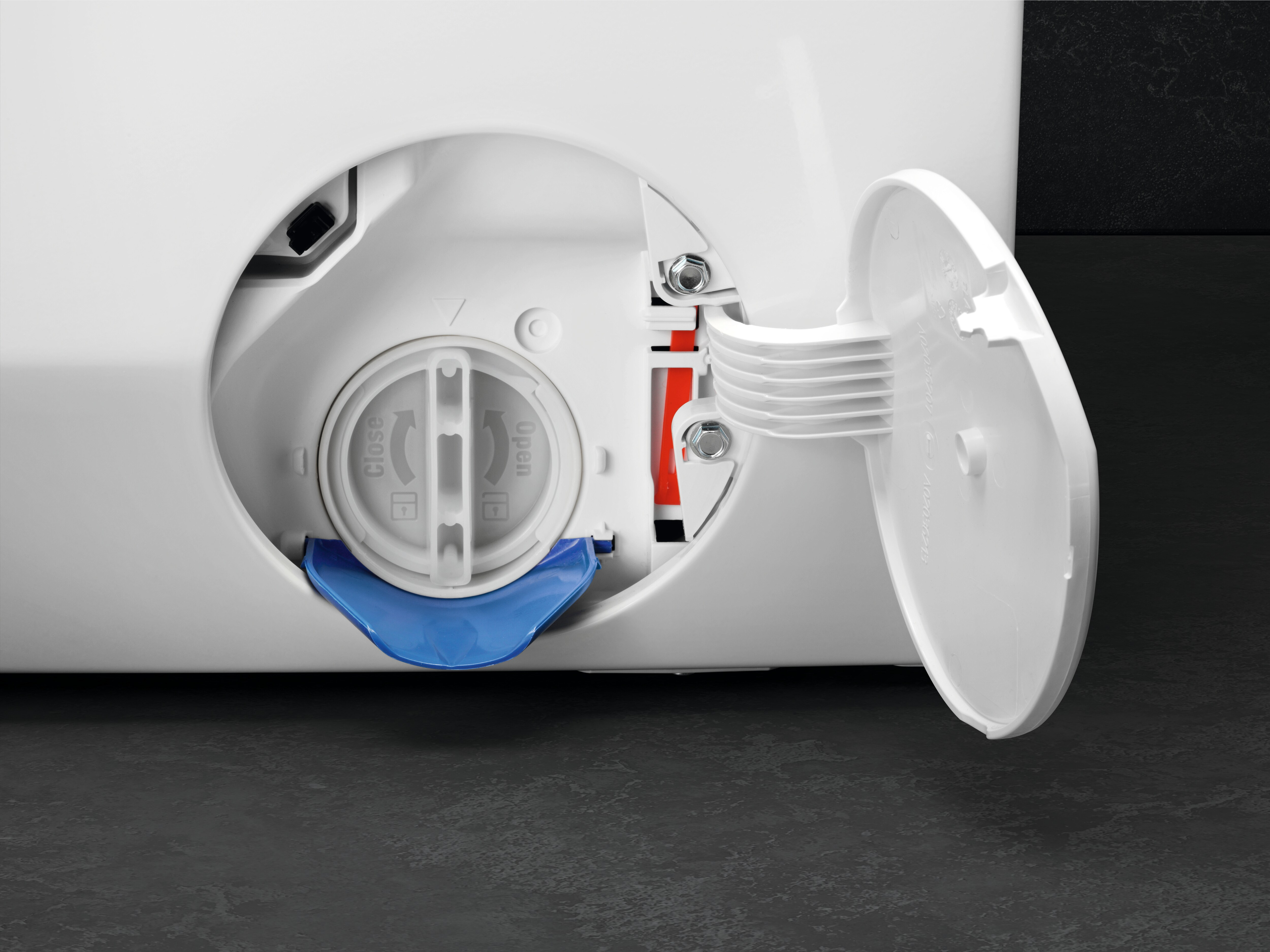Washing machine water filter access, open. White plastic cover, blue water catch below.