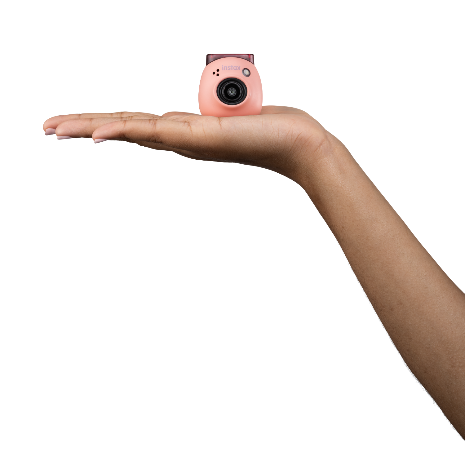 Hand holding a small pink camera. Black background.