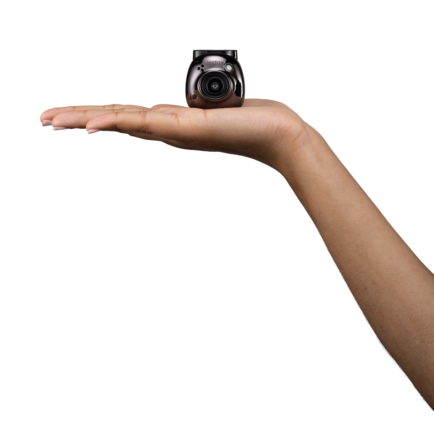 A person holding a small brown camera on their open palm against a black background.
