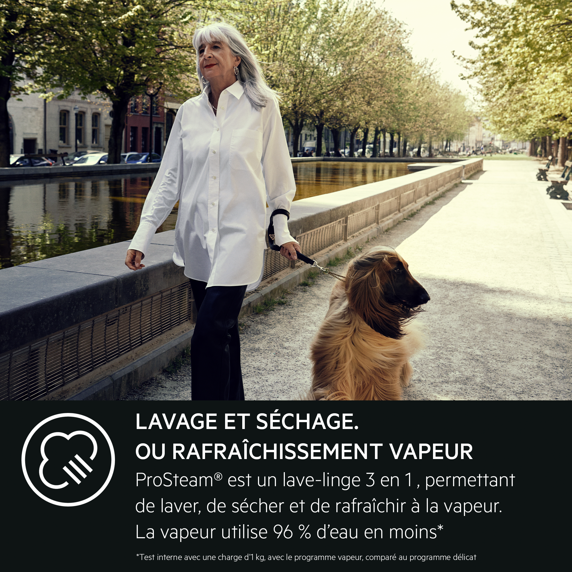 Une femme promène un chien en laisse près d'un canal. Des arbres bordent le chemin. Le chien est un Afghan.