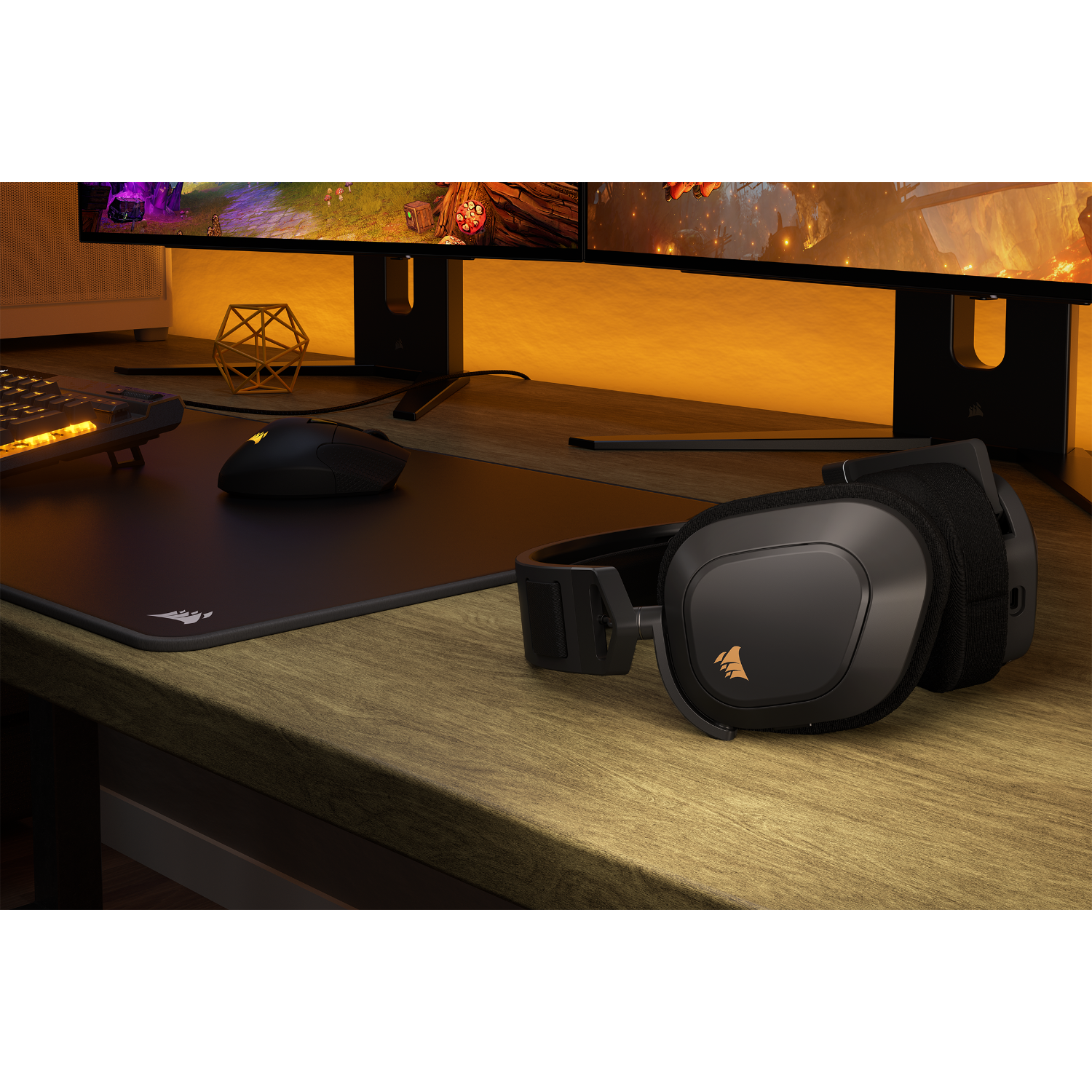 Gaming setup with headset, mouse, keyboard, and monitors. Monitors display a game scene with golden light.