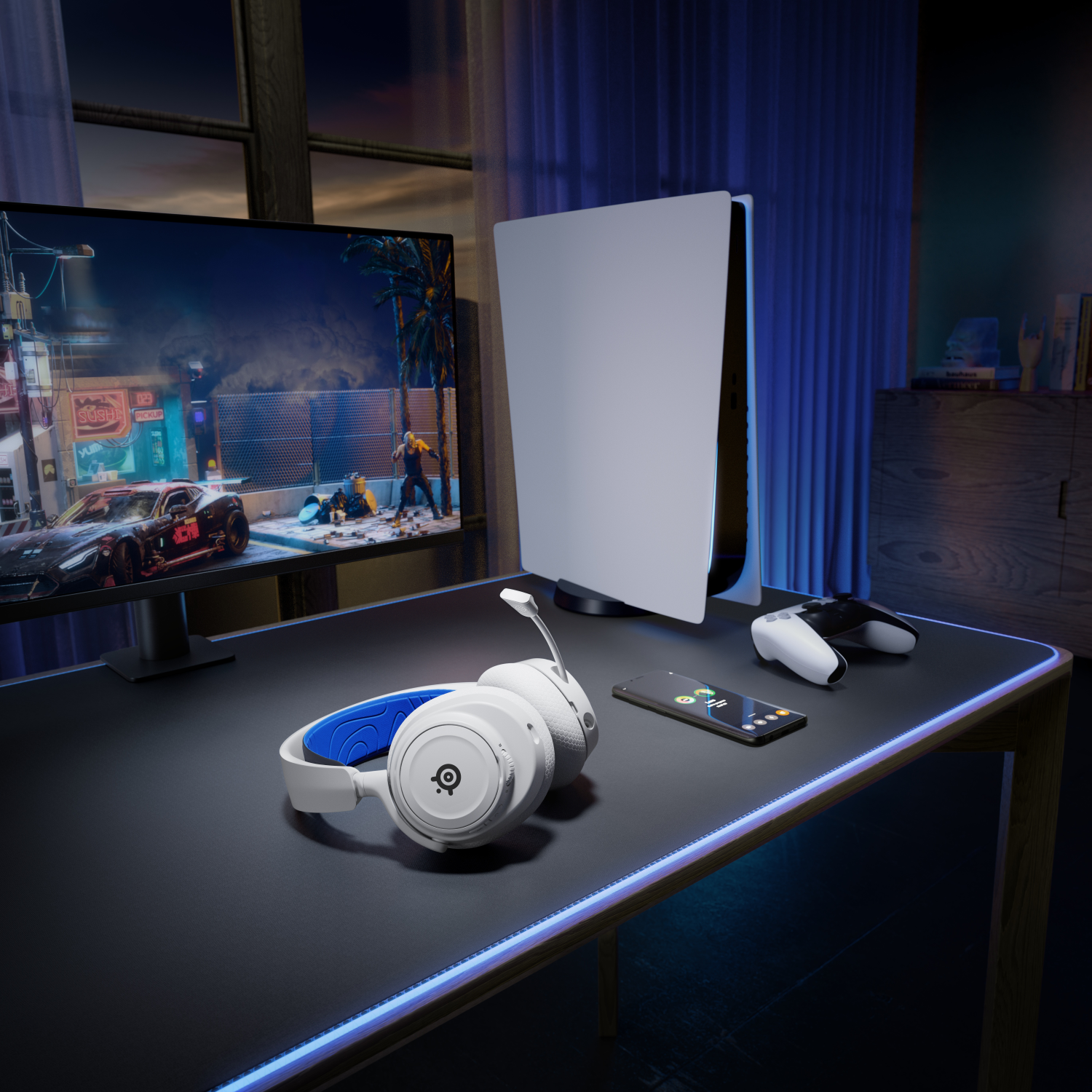 A gaming setup with a monitor, console, headphones, controller, and a smartphone on a desk.