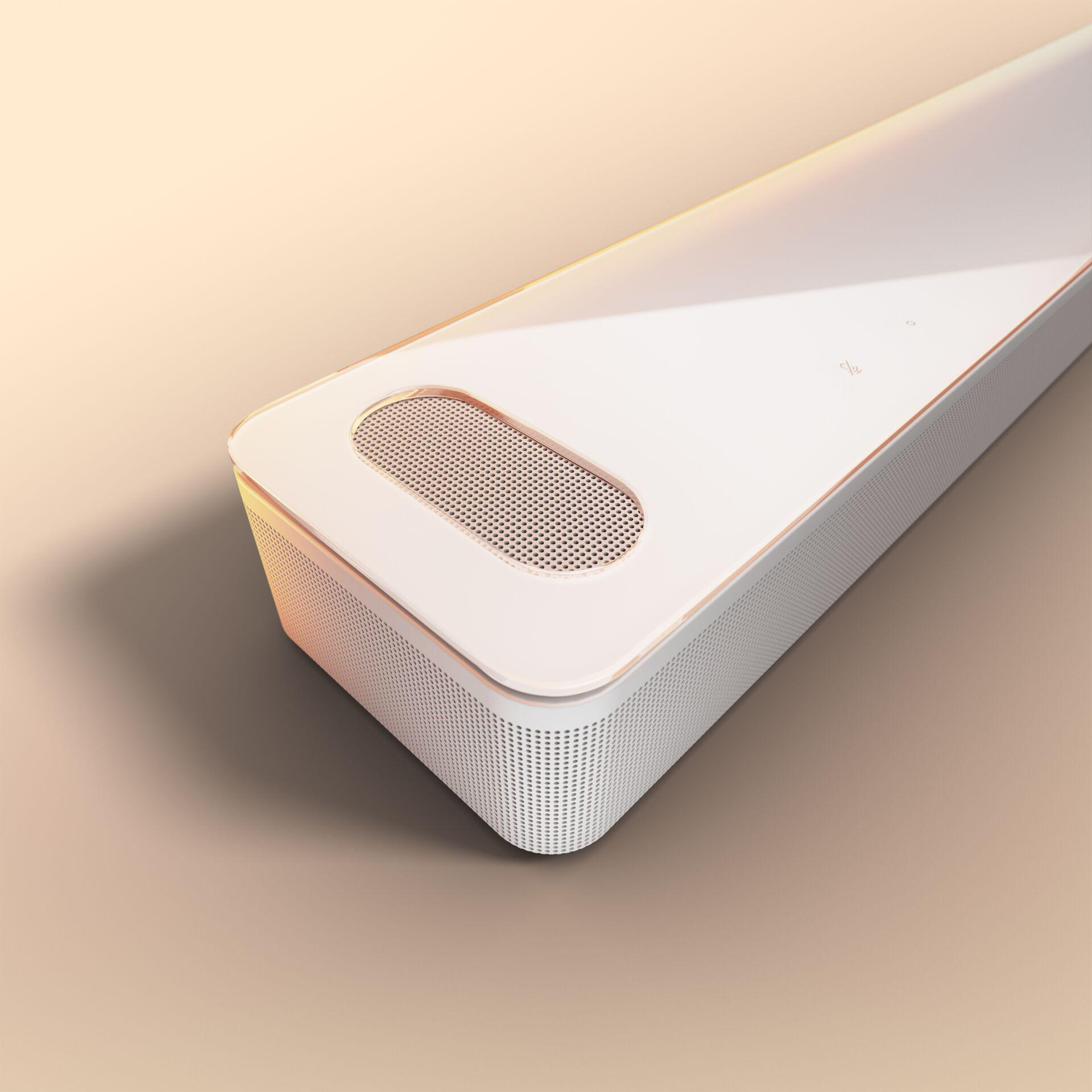 Weiße und goldene Soundbar auf hellbrauner Oberfläche, schräge Ansicht.