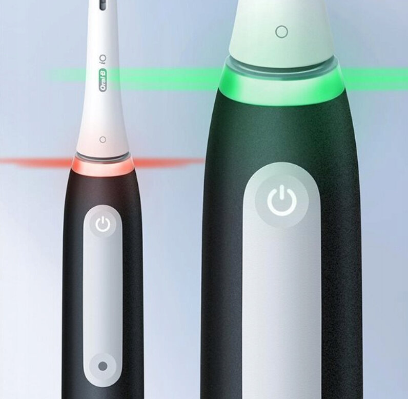 Dwie elektryczne szczoteczki do zębów Oral-B iO. Jedna pokazuje czerwone, druga zielone światło.