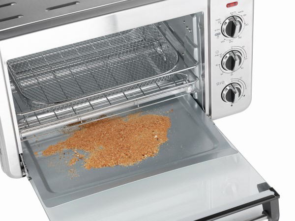 Egy kis ezüst kenyérpirító sütő nyitott ajtóval. Egy tálca morzsával látható.