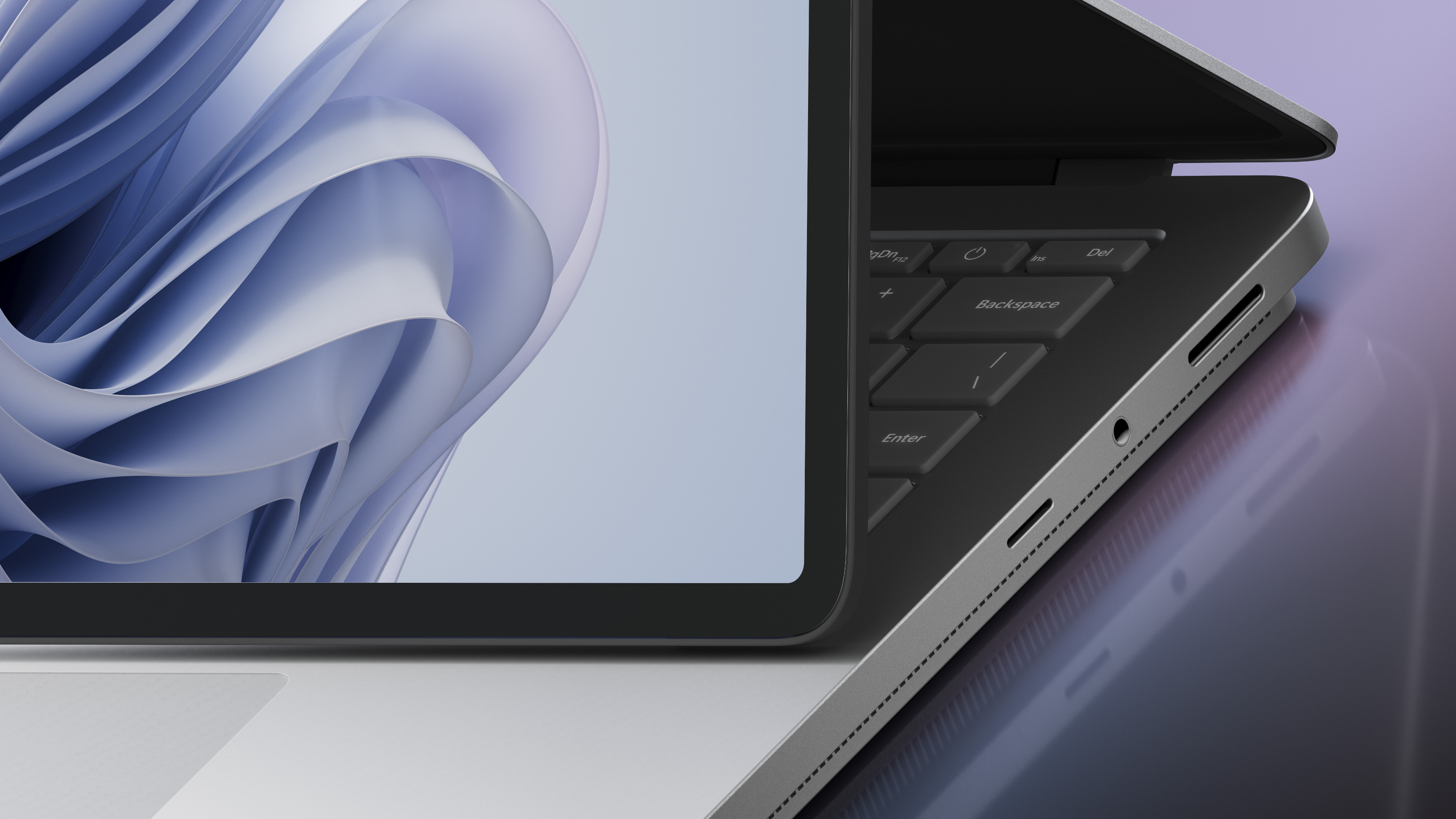 Laptop auf einer Oberfläche, der Deckel geöffnet. Tastatur sichtbar, der Bildschirm zeigt abstrakte blaue Formen.