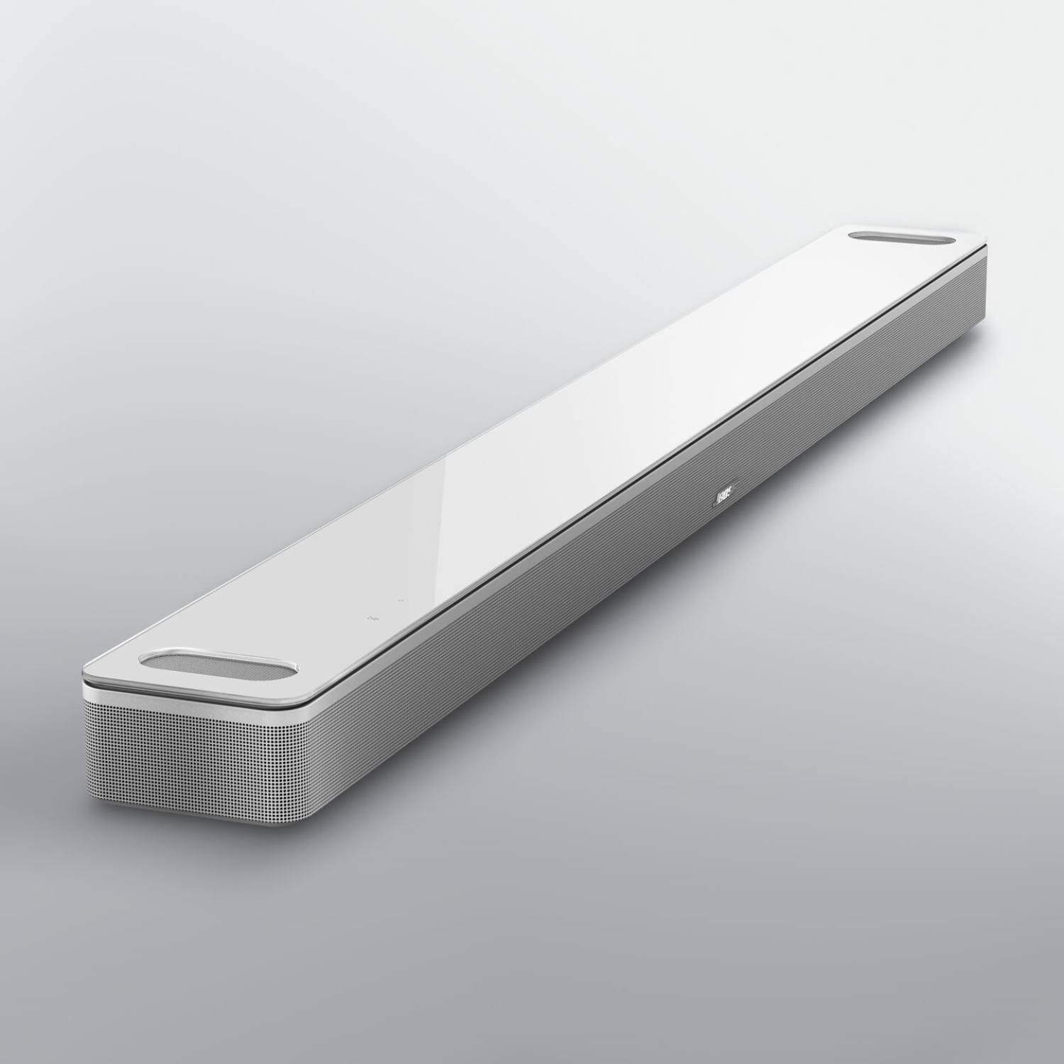 A white soundbar with a glossy top surface and grey sides. It is on a light grey surface.
