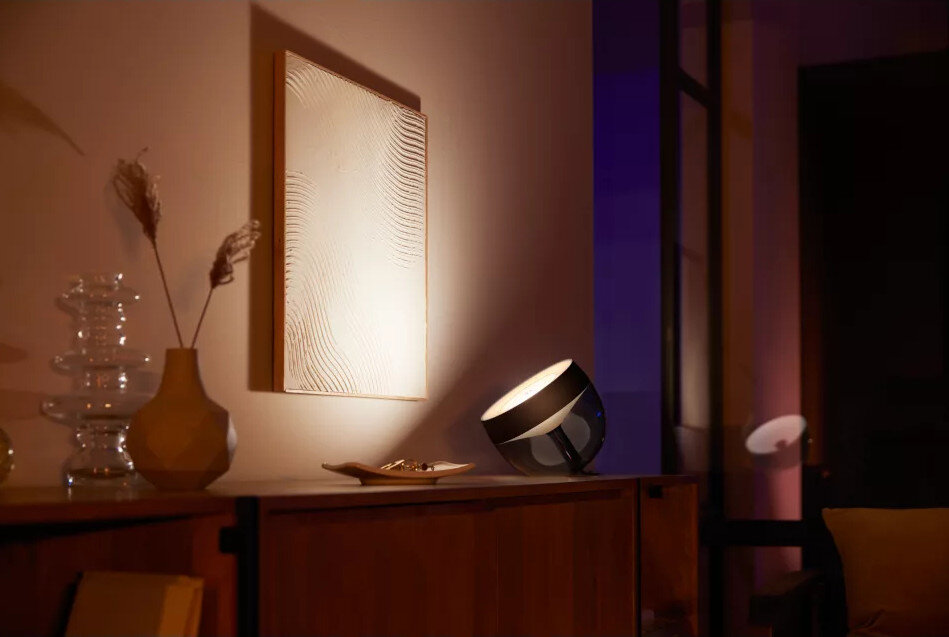 Nowoczesna scena w salonie z lampą, obrazem i drewnianymi meblami.