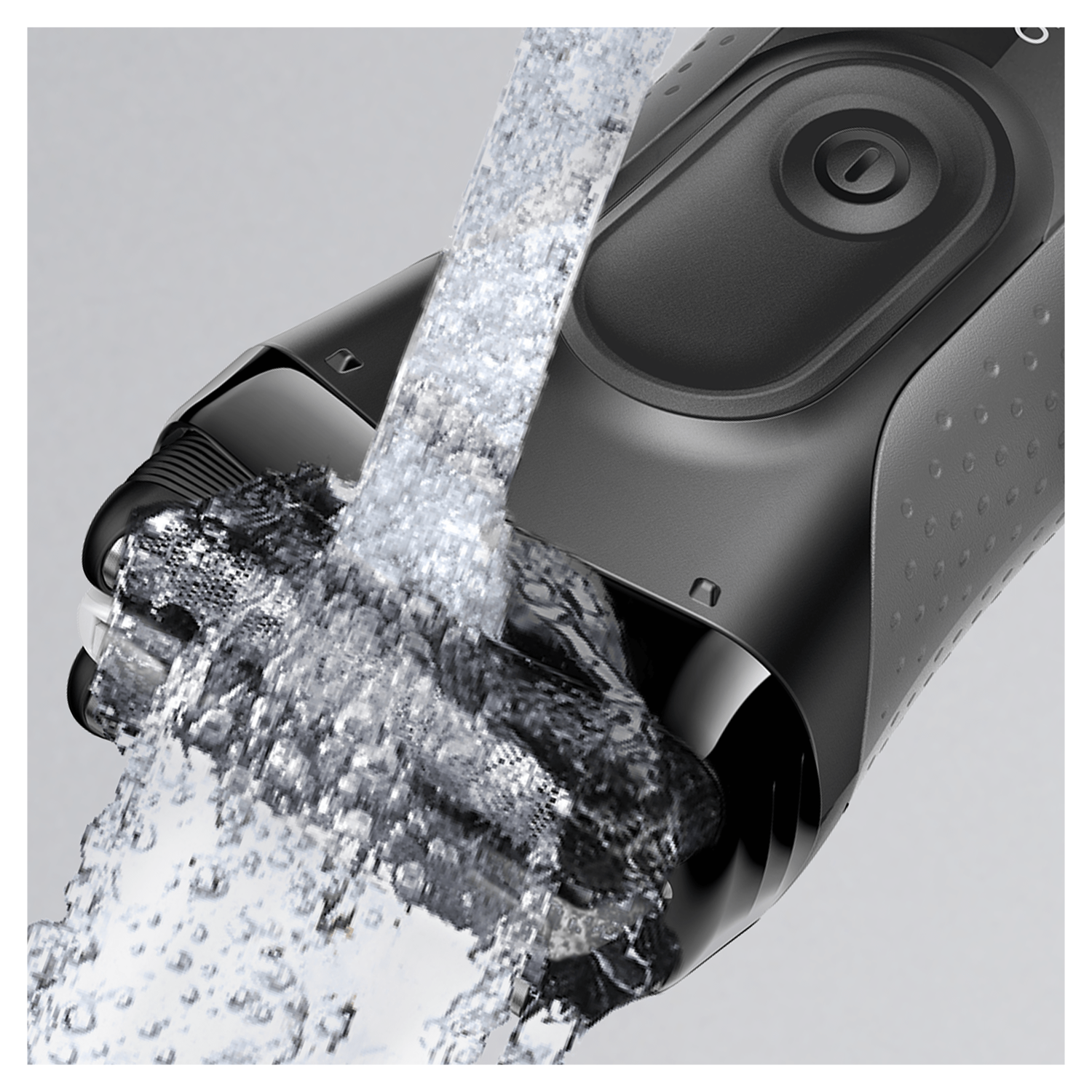 Black shaver being rinsed with water. Water streams over the blades, cleaning them.