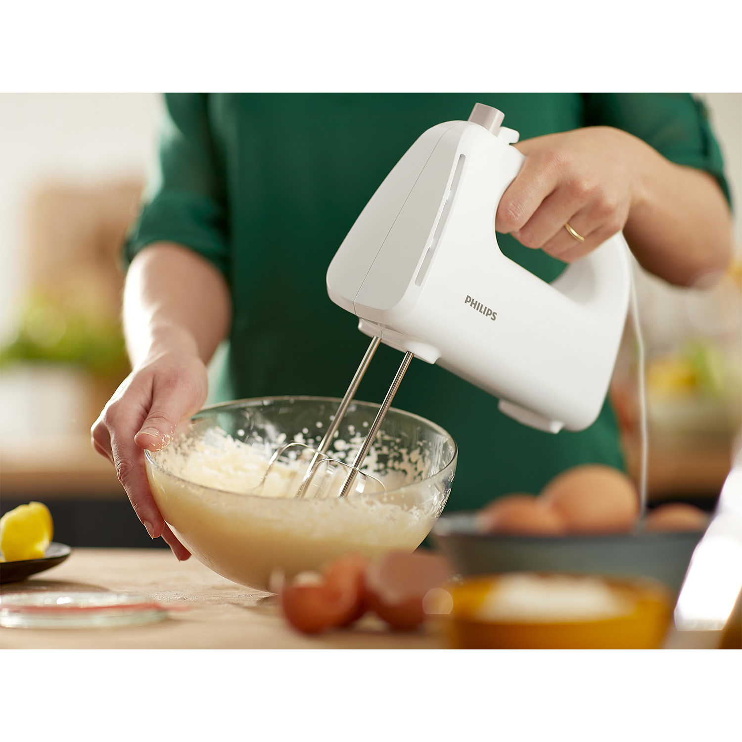 Una persona usa un frullatore a mano bianco, mescolando gli ingredienti in una ciotola.