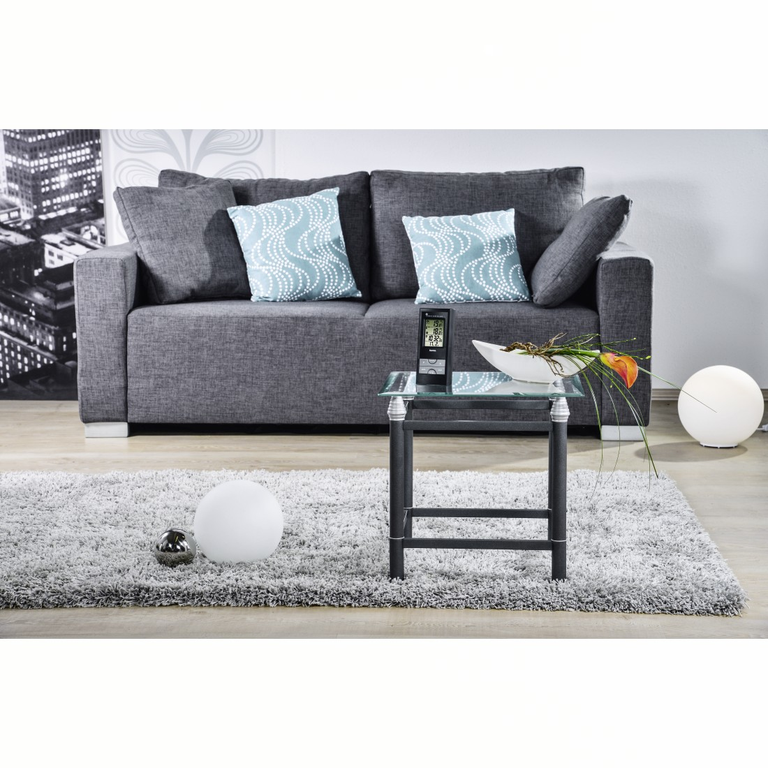 Salón con sofá gris, alfombra, mesa y decoración.